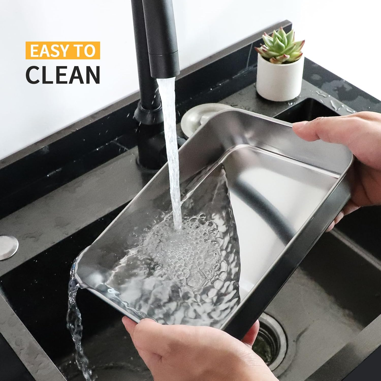 Wasser läuft aus schwarzem Hahn in ein Edelstahlblech über einem schwarzen Spülbecken.
