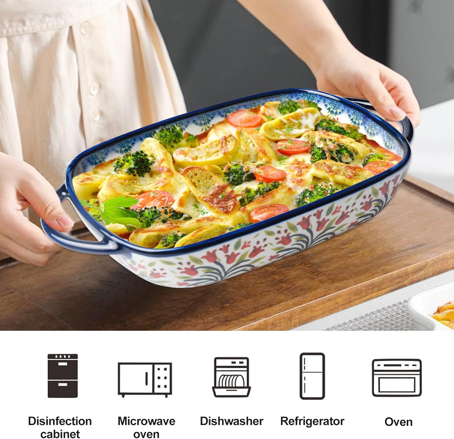 Person hält eine geblümte Keramikauflaufform mit gebackenem Essen, darunter Brokkoli und Tomaten.