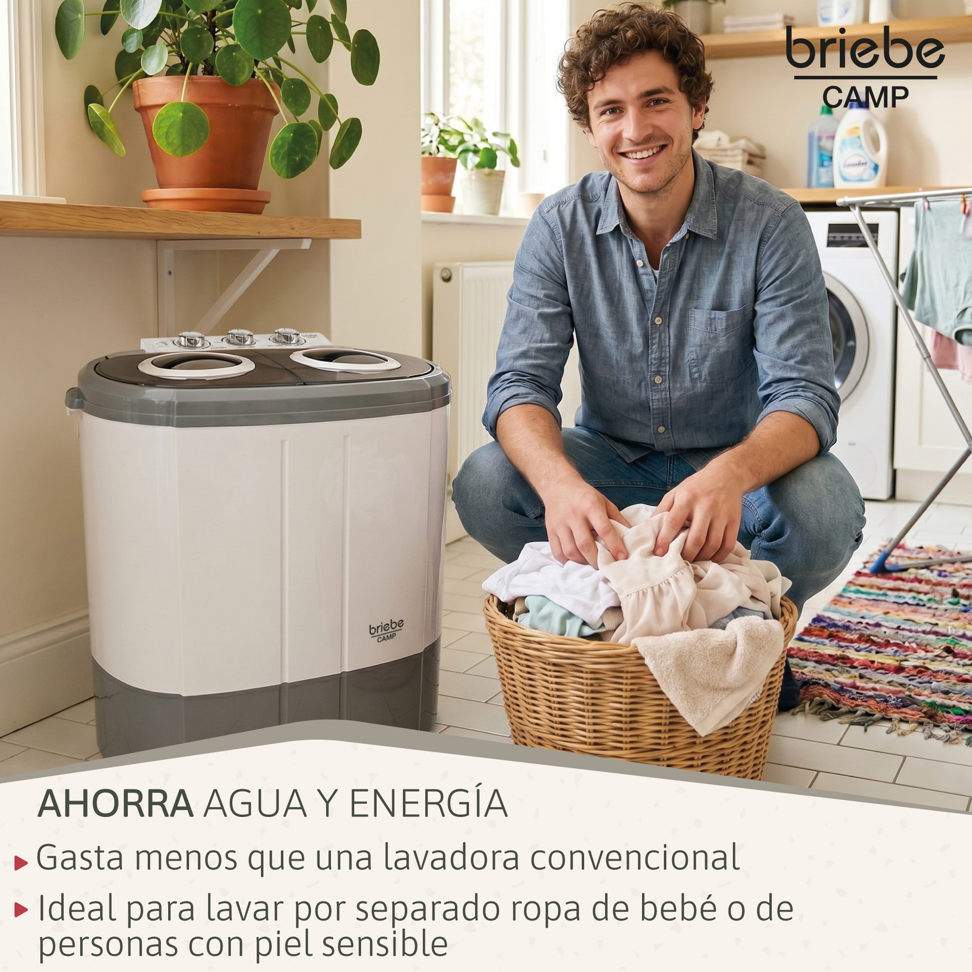 Un hombre sonriente se arrodilla junto a un cesto de ropa y una lavadora portátil en una habitación luminosa.