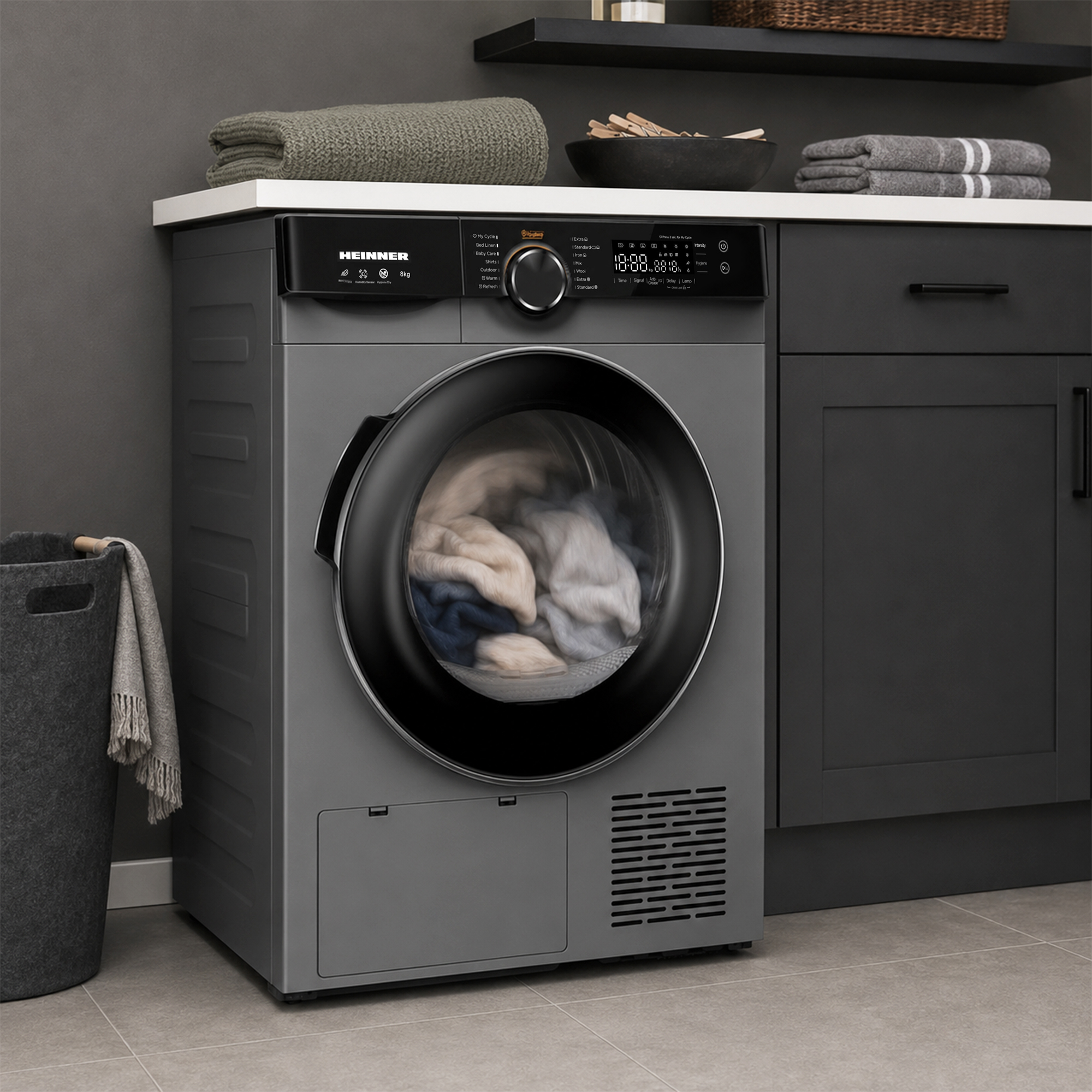 Grauer Heinner Frontlader-Waschtrockner mit Wäsche in der Trommel in einer modernen Küche mit dunklen Möbeln.