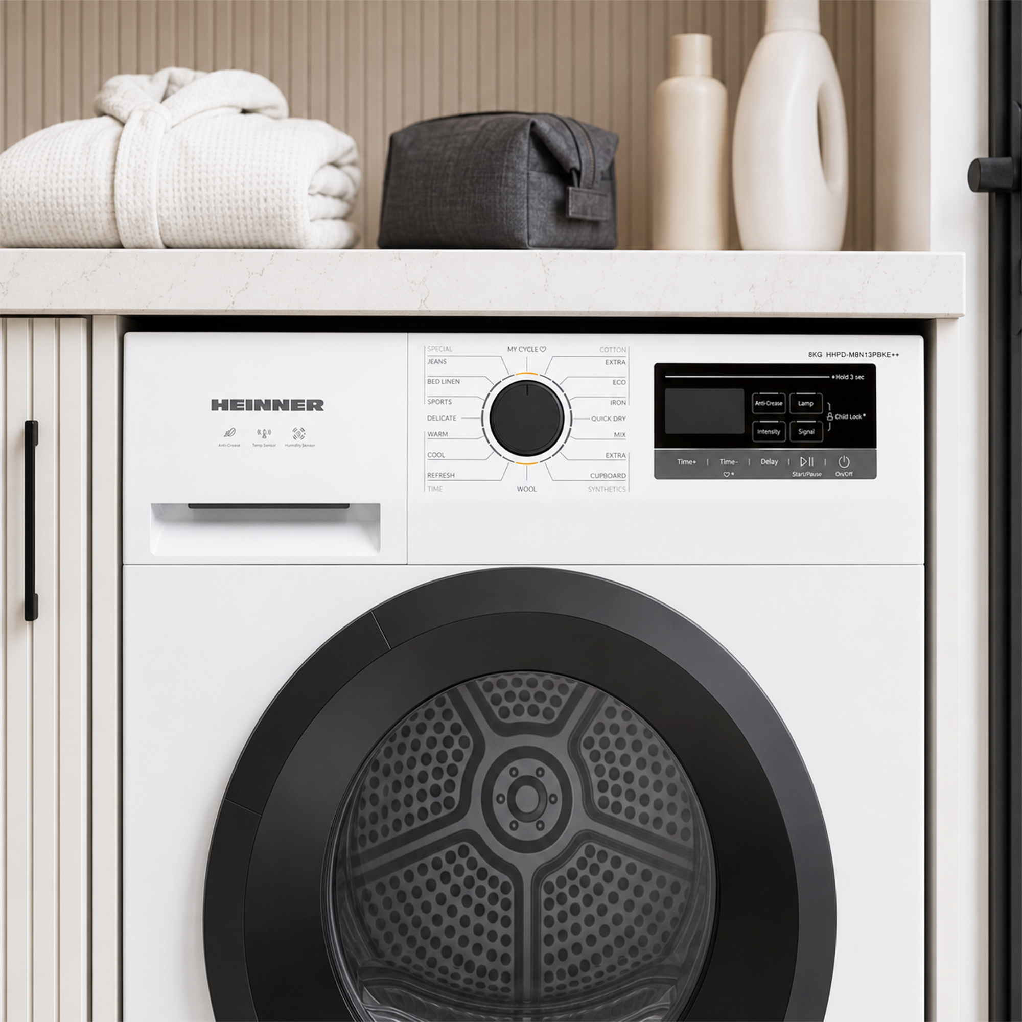 Un sèche-linge blanc Heinner avec une porte noire et un panneau de commande dans une pièce moderne.