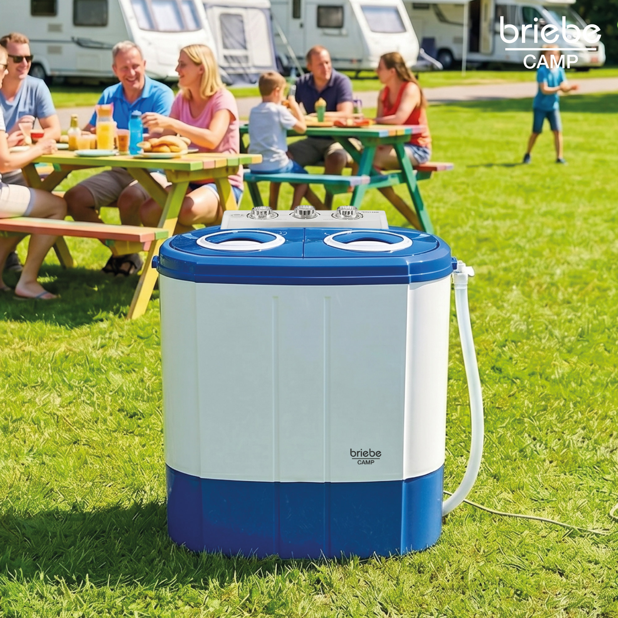 Lavadora portátil de camping blanca y azul en primer plano, con personas sentadas en mesas de pícnic al fondo.