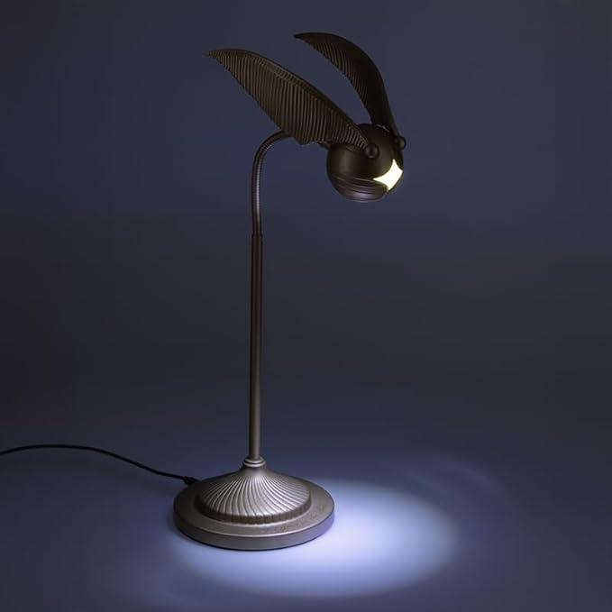 Una lámpara de escritorio de metal con forma de la Snitch Dorada de Harry Potter, emitiendo una luz suave.