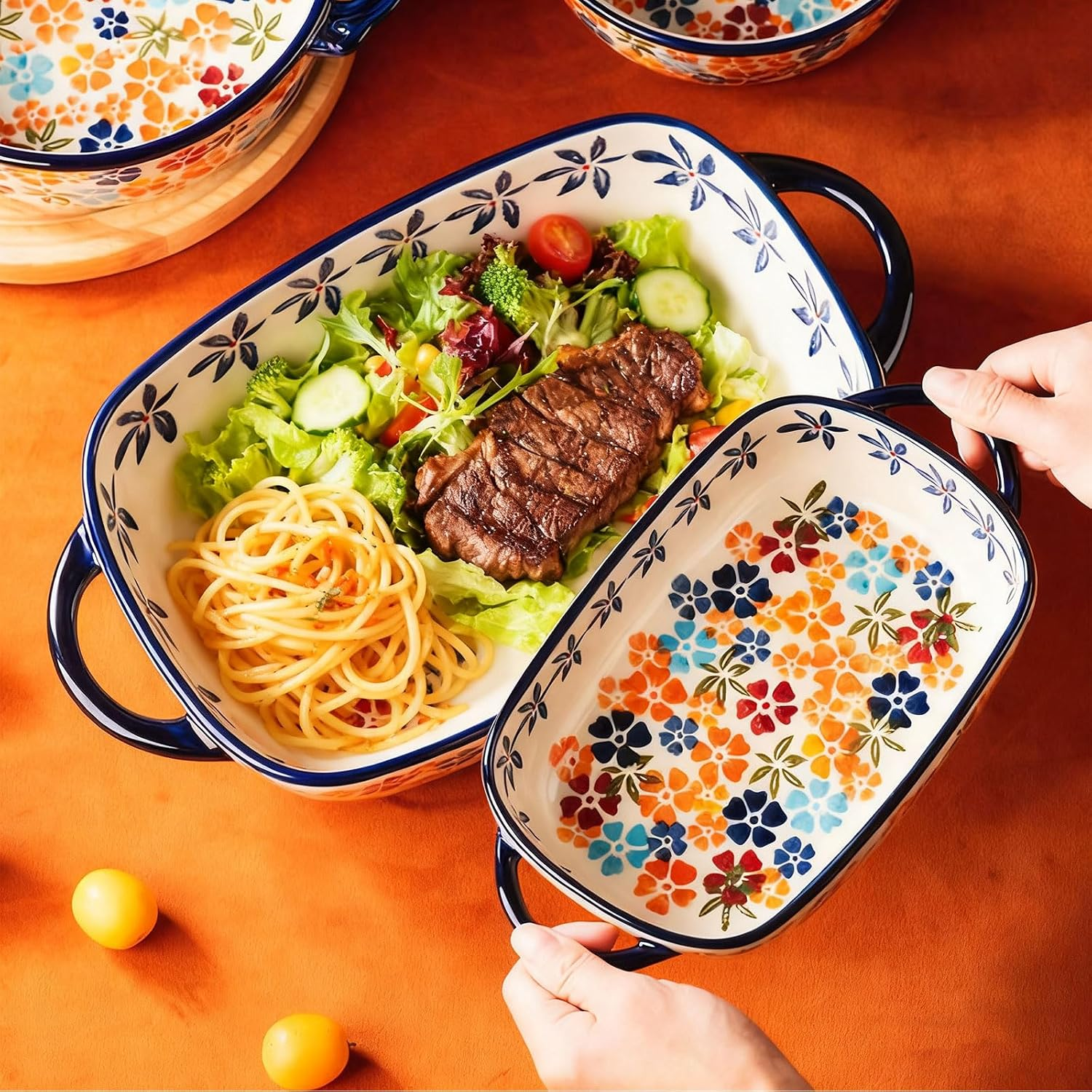 Eine blau-weiß gemusterte Keramikschüssel mit Steak, Salat und Spaghetti steht auf einem orangefarbenen Tisch.