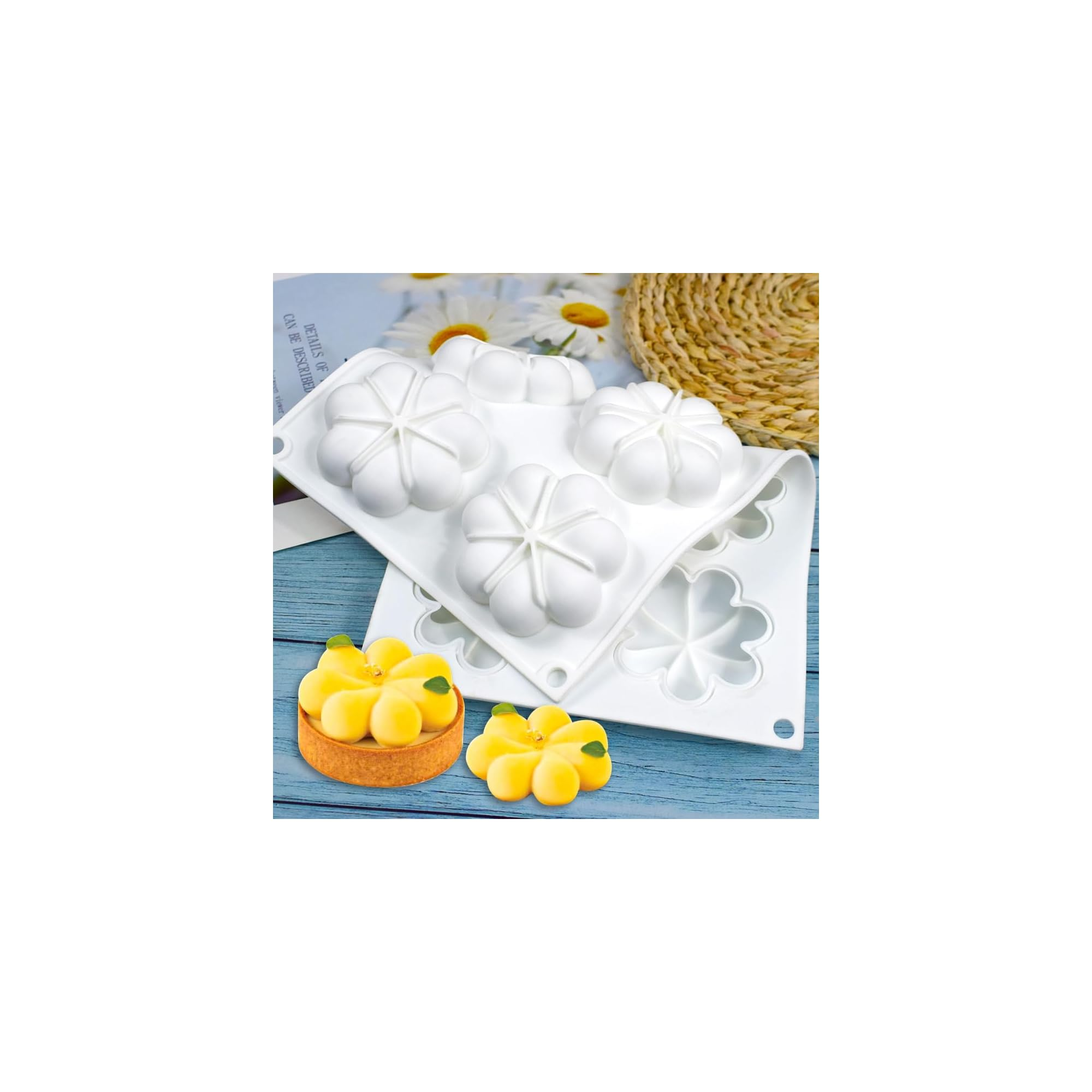 Weiße Silikon-Backform mit Blumenmuster und zwei fertigen gelben Kuchen auf einem blauen Holzgrund.