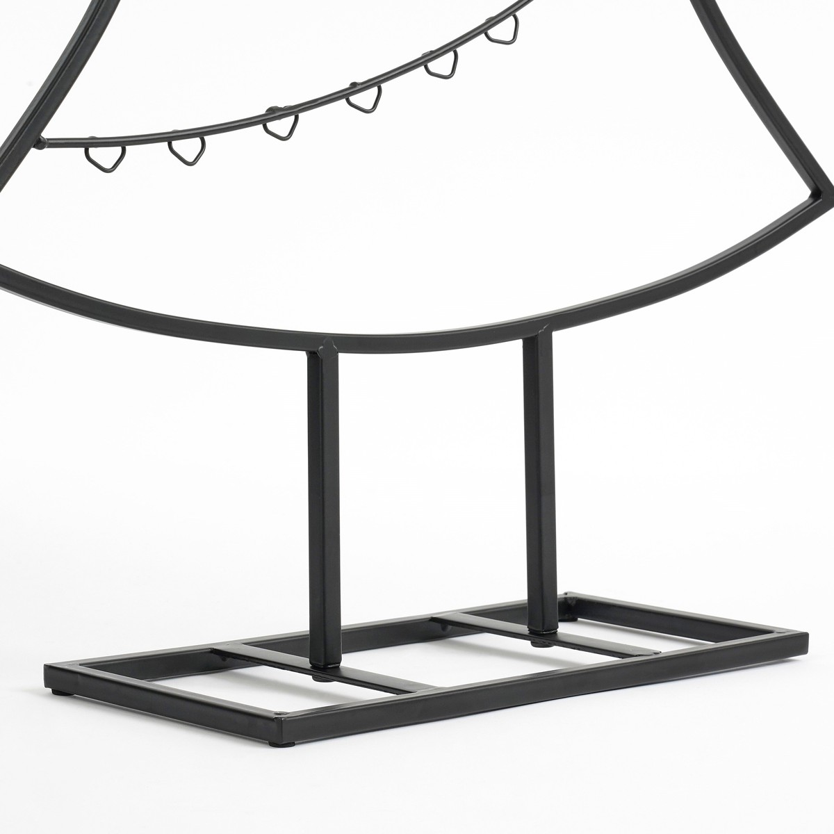 Un support en métal noir arqué avec de petits crochets suspendus sur une base rectangulaire sur fond blanc.