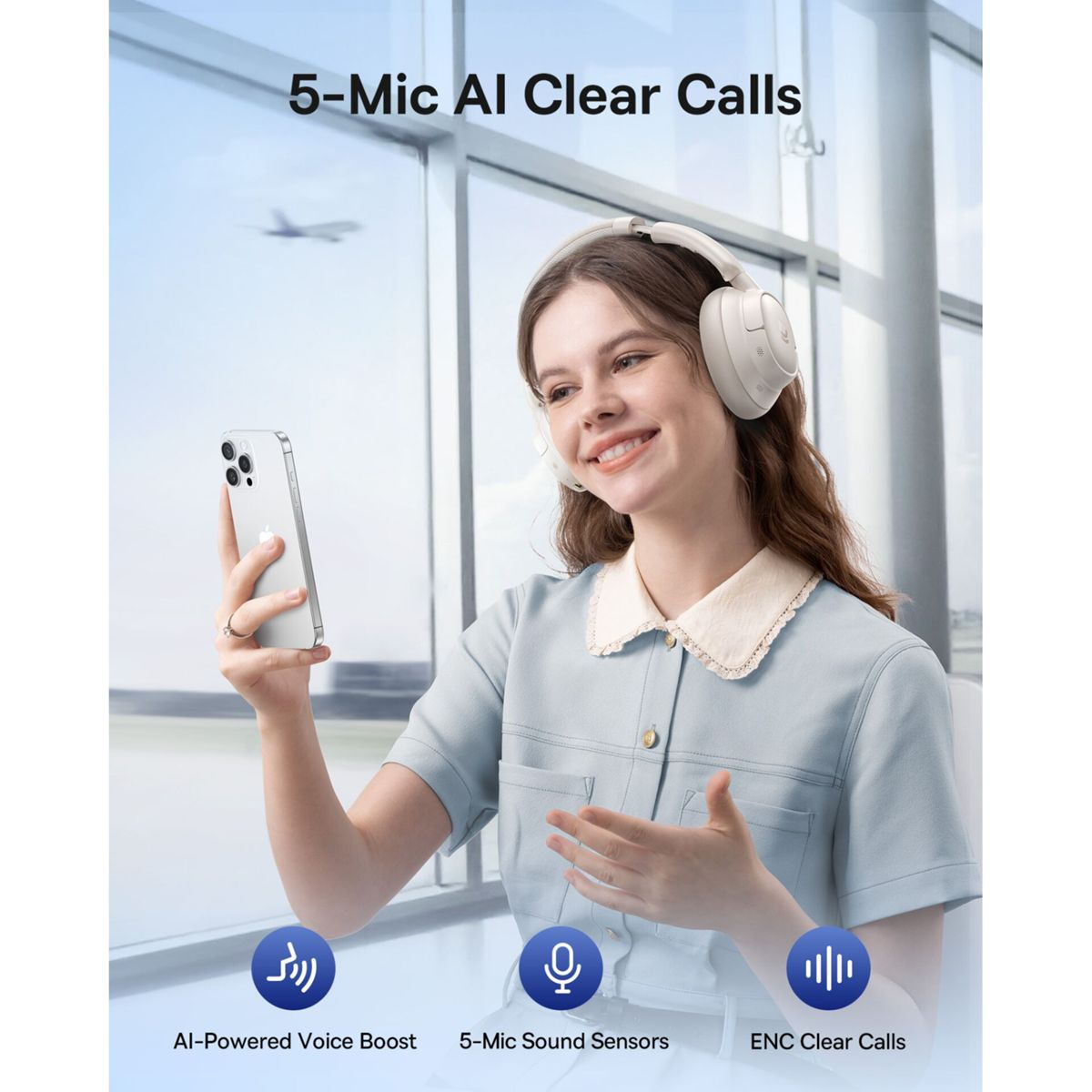 Une femme souriante portant un casque beige tient un smartphone devant une grande fenêtre d'aéroport.