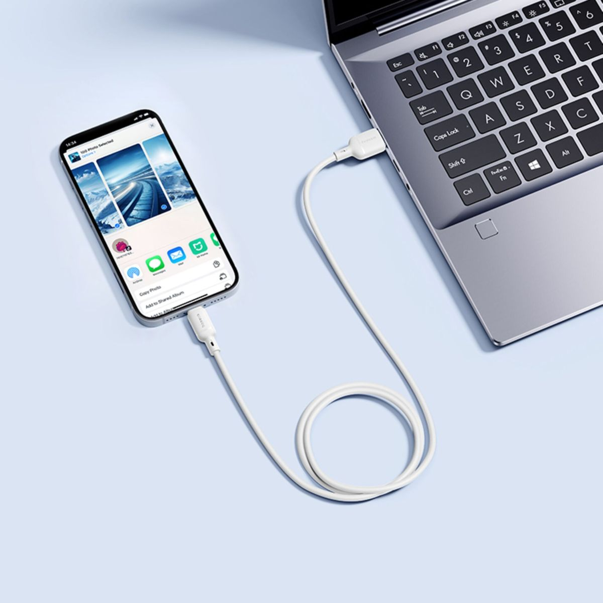 Uno smartphone è collegato a un computer portatile tramite un cavo USB bianco.
