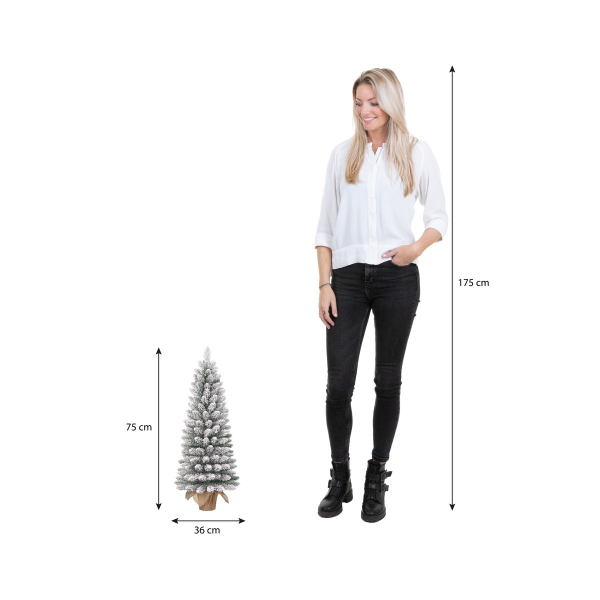 Een vrouw staat naast een kleine, besneeuwde kerstboom met hoogte-afmetingen in centimeter.