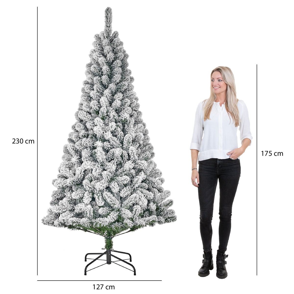 Een besneeuwde kunstkerstboom van 230 cm hoog naast een vrouw van 175 cm voor de schaal.