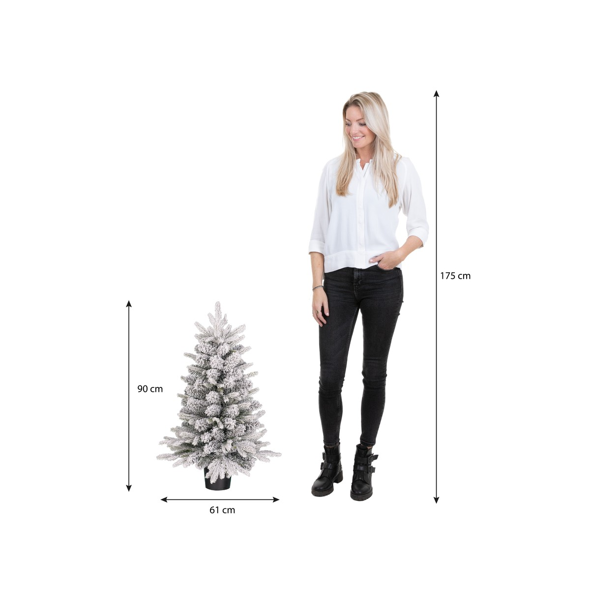 Een vrouw staat naast een kunstkerstboom van 90 cm met sneeuw.