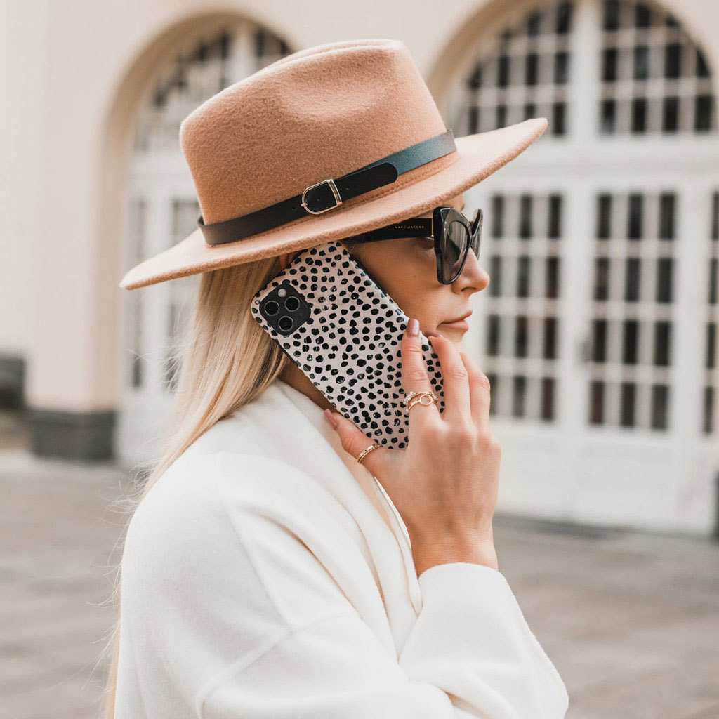 Donna con cappello e occhiali da sole parla al telefono con cover dalmata.