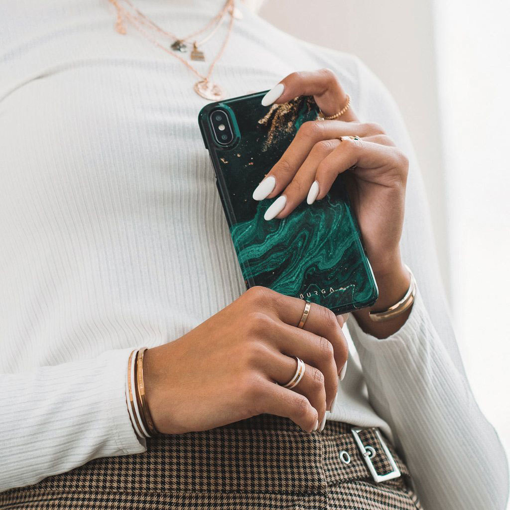 Eine Person mit weißem Pullover hält ein Smartphone mit grün-schwarzem Marmormuster.