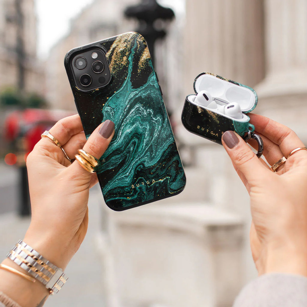 Mains tenant une coque de téléphone en marbre vert et noir et un étui AirPods assorti à l'extérieur.