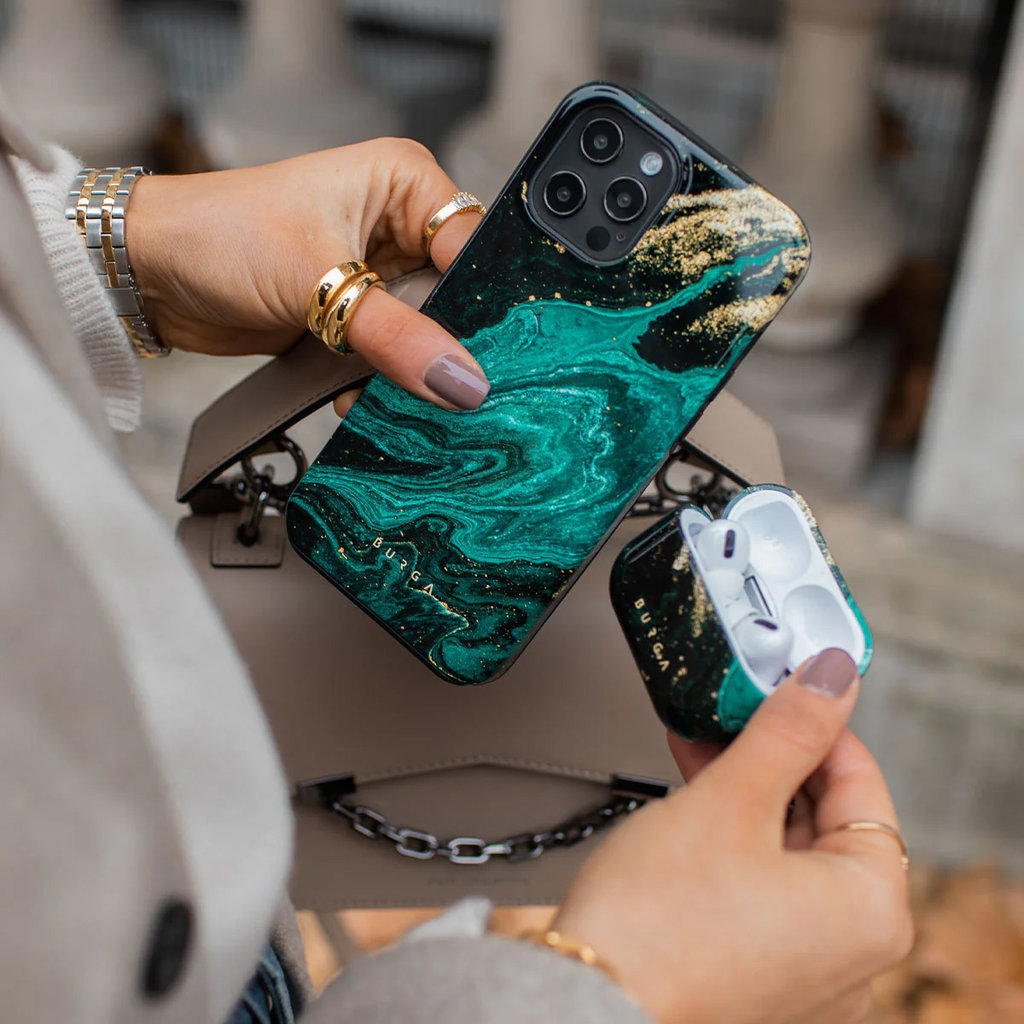 Une main tient une coque de téléphone en marbre vert et doré et un étui AirPods assorti.