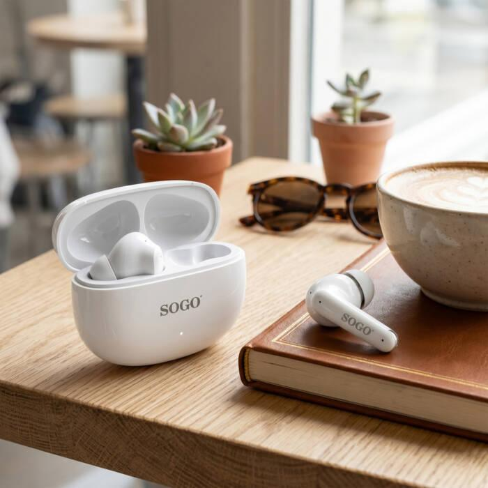 Custodia per auricolari Sogo bianca con auricolare, taccuino, tazza di caffè e succulente su tavolo in legno.