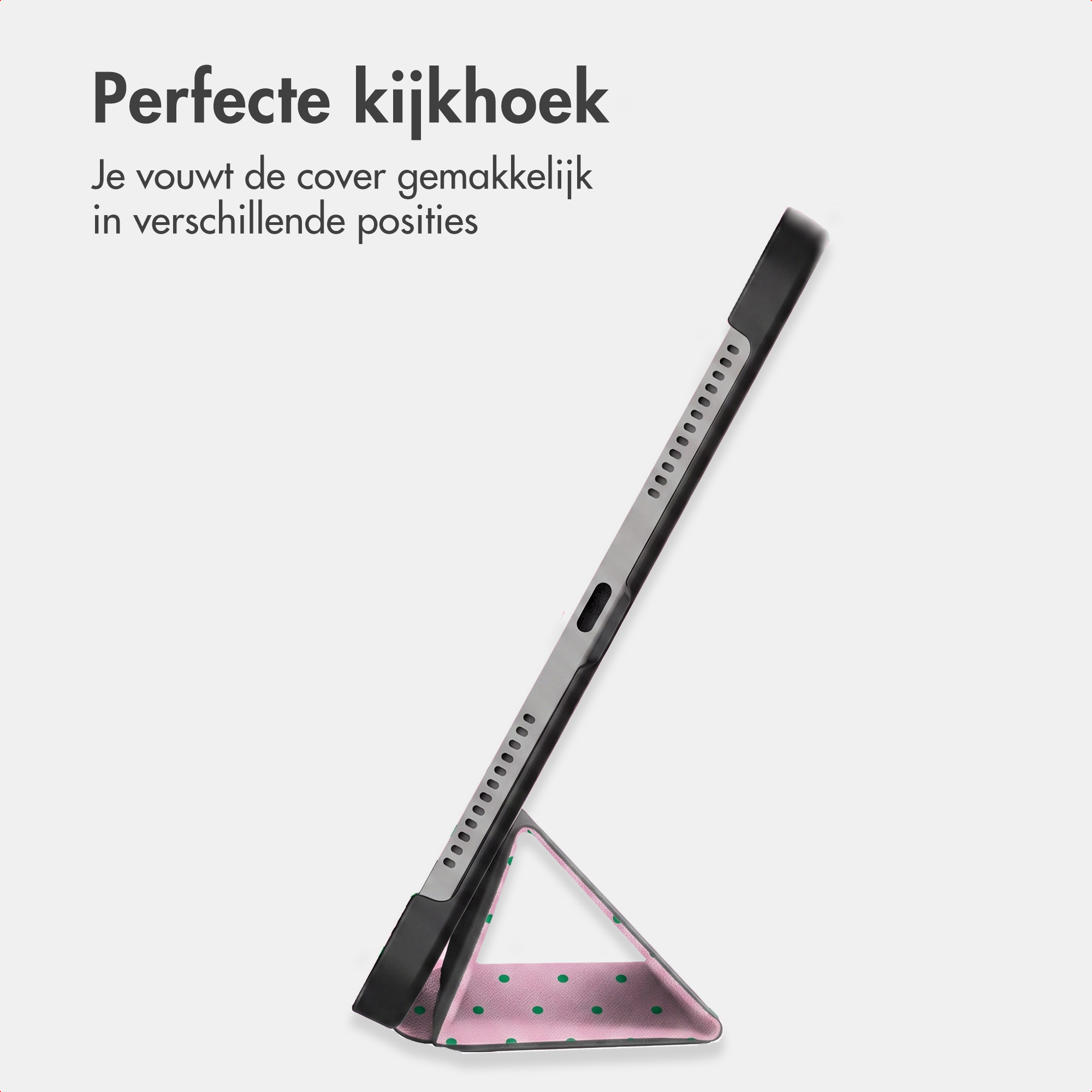 Une tablette dans une coque sombre, soutenue par un support rose à pois verts, sur fond clair.