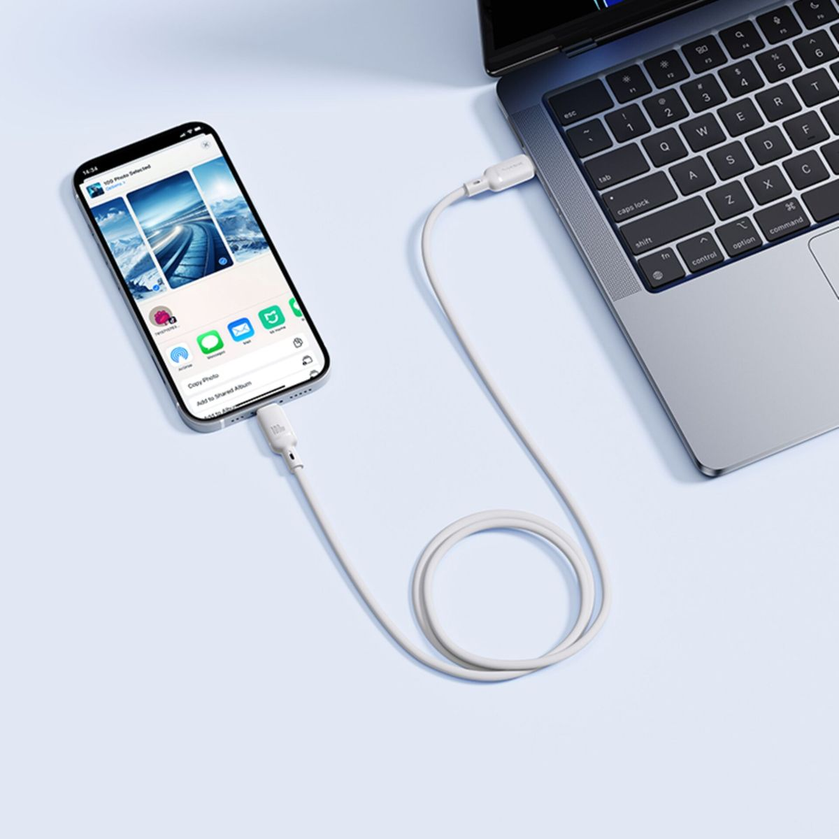 Uno smartphone è collegato a un computer portatile tramite un cavo USB bianco.