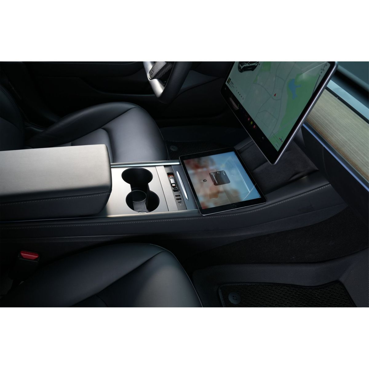 Interior de un auto moderno con asientos de cuero negro, una pantalla táctil central y una tableta en la consola.