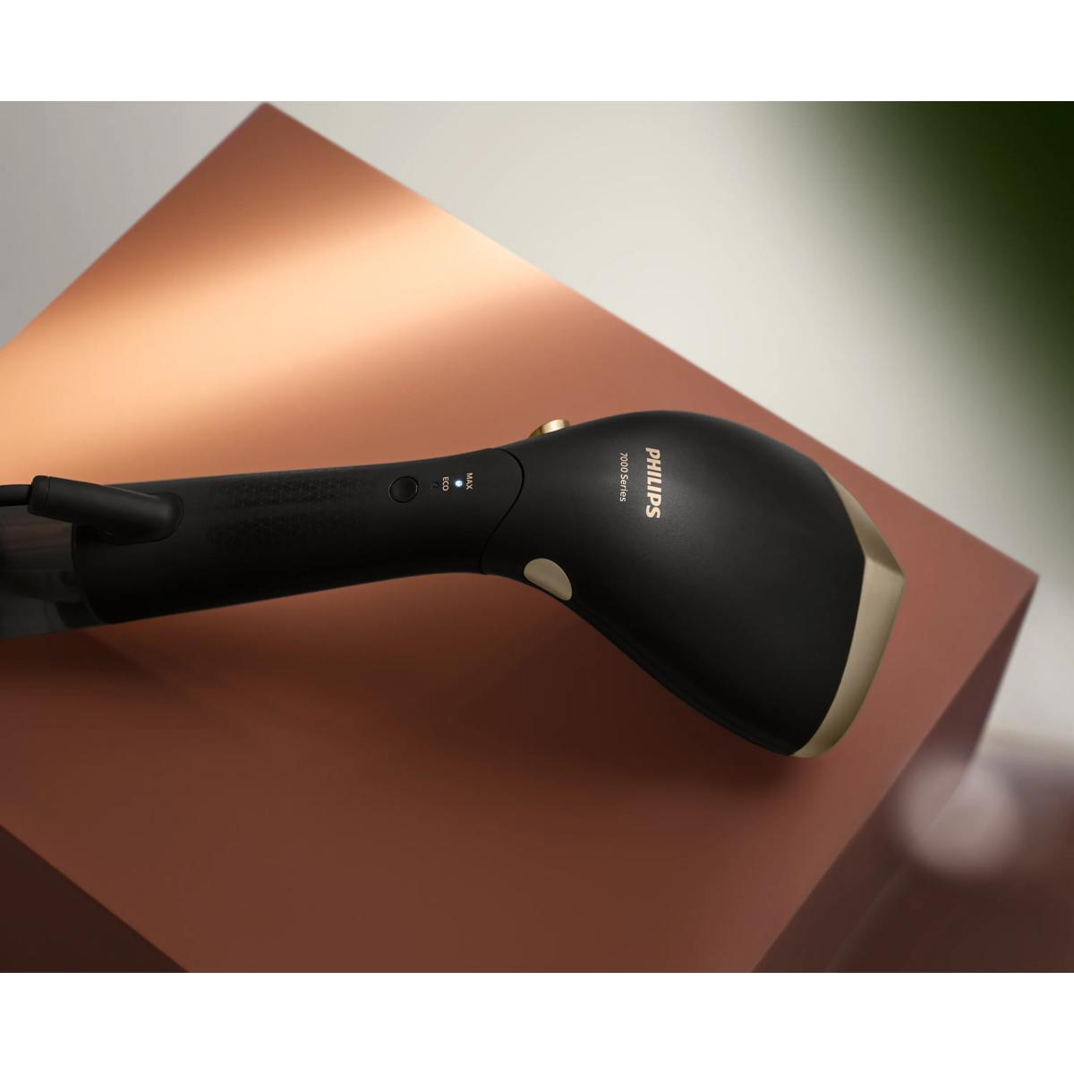 Siyah bir Philips 7000 Serisi el tipi buharlı ütü kırmızı bir yüzey üzerinde duruyor.