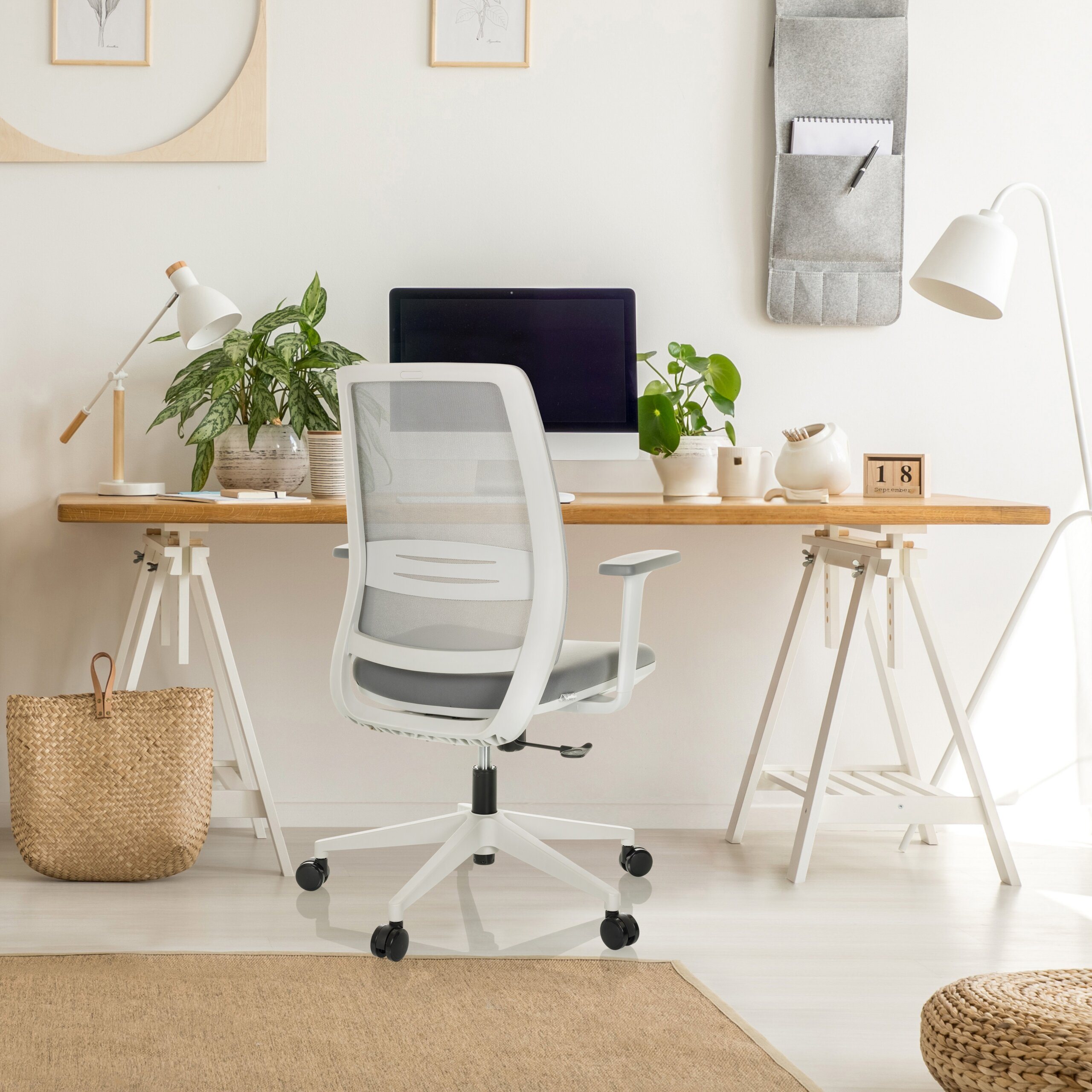 Ein modernes Homeoffice mit Holztisch, weißem Bürostuhl, Computer, Lampen und Pflanzen.
