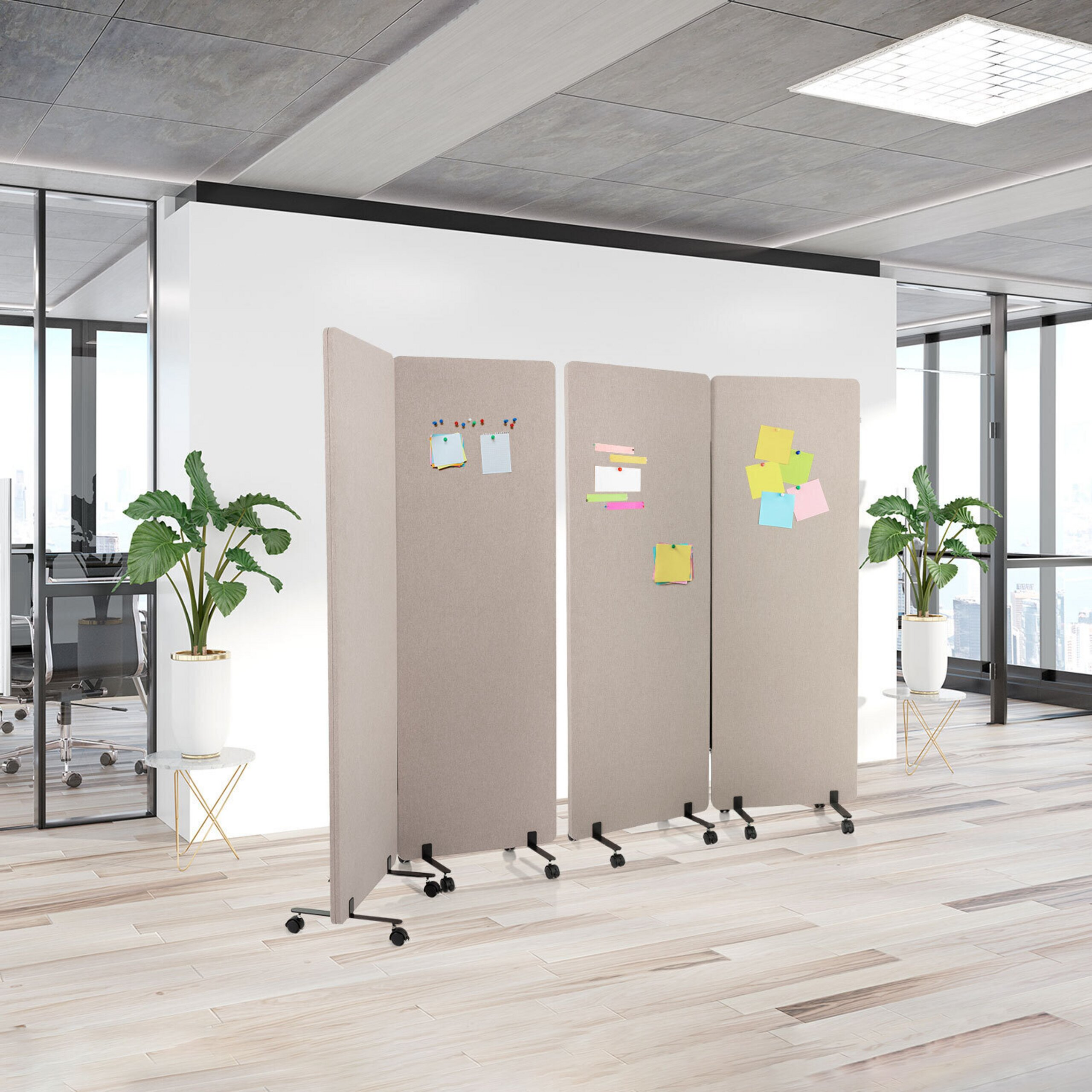 Eine beige mobile Trennwand mit Haftnotizen steht in einem hellen Büro mit Topfpflanzen und Holzböden.