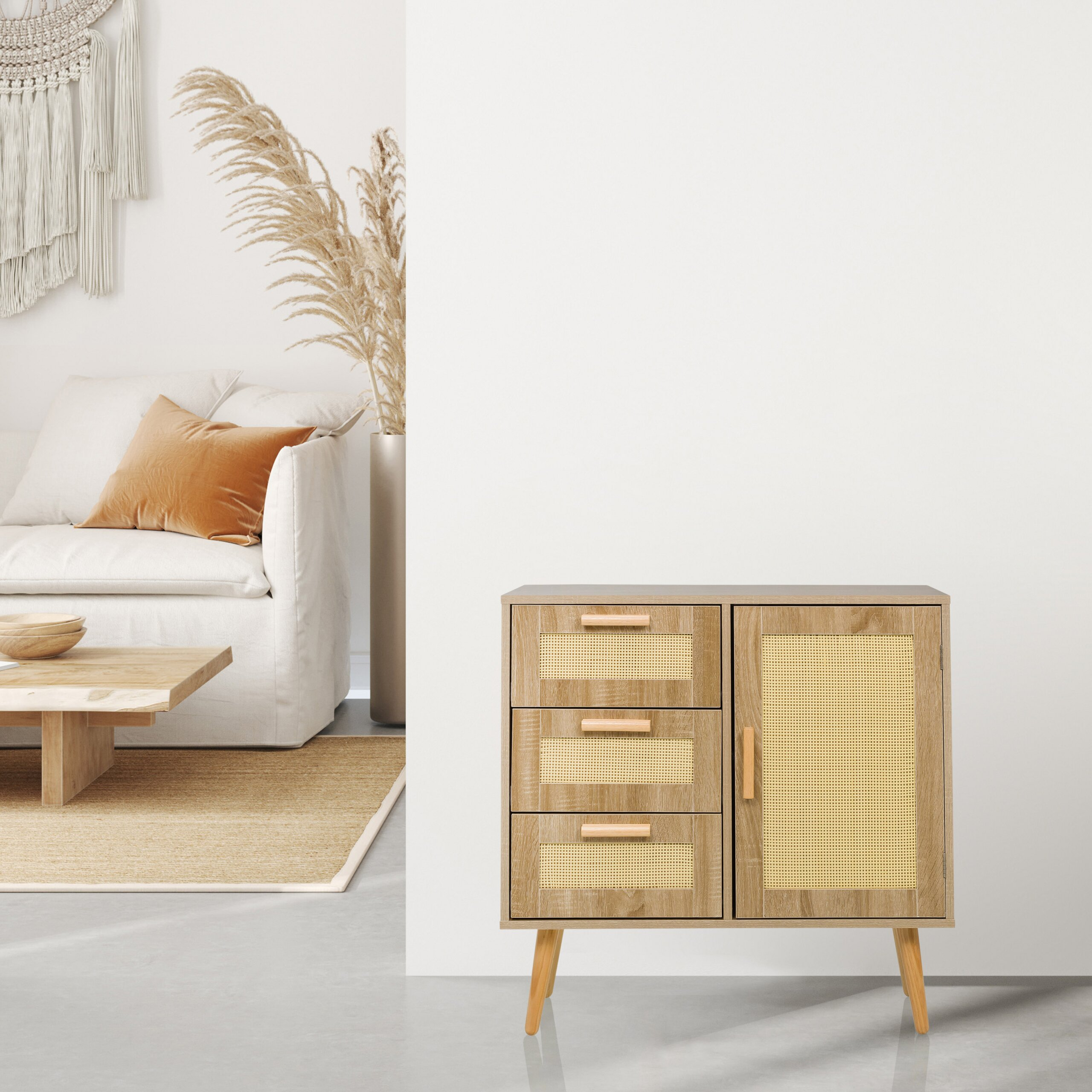 Ein Holzschrank mit Rattandetails steht vor einer weißen Wand, links sieht man ein Wohnzimmer.