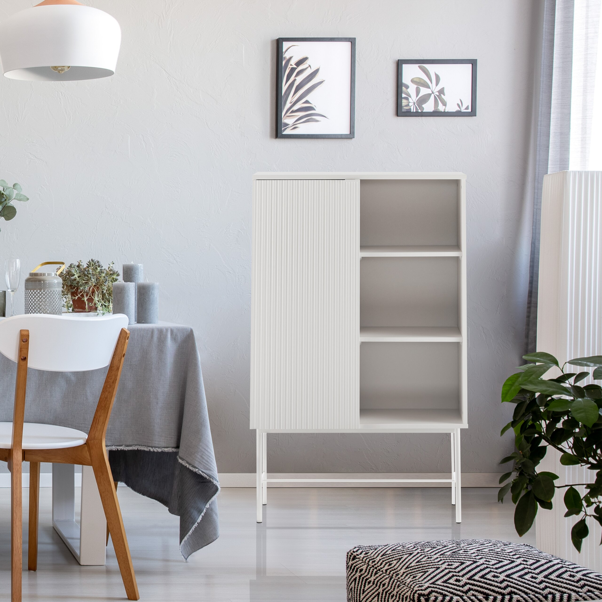 Ein weißer Schrank mit Lamellentür und offenen Regalen steht in einem hellen Raum neben einem gedeckten Tisch.
