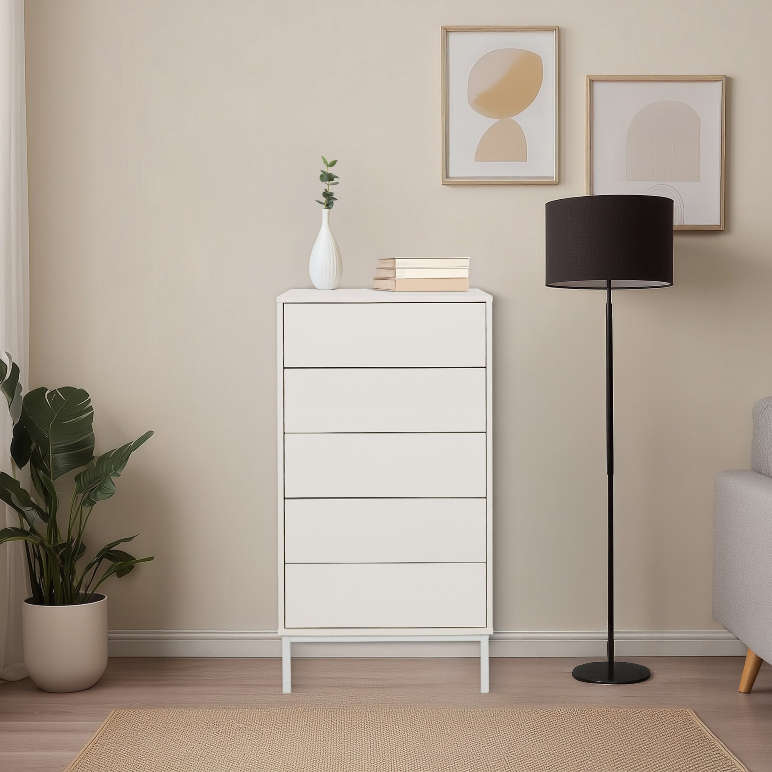 Eine weiße Kommode mit Vase, Büchern, zwei gerahmten Bildern und einer Stehlampe auf einem hellen Teppich.