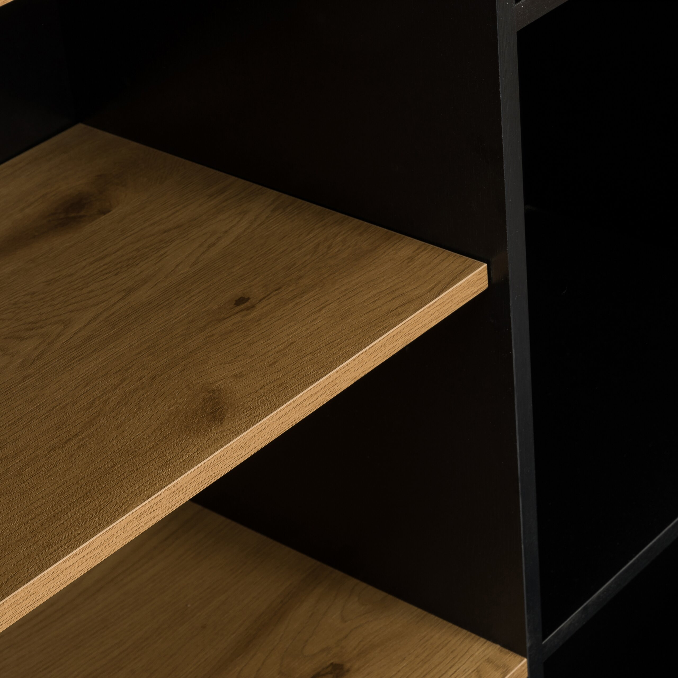 Nahaufnahme eines Bücherregals mit Holzregalbrettern und schwarzem Korpus.