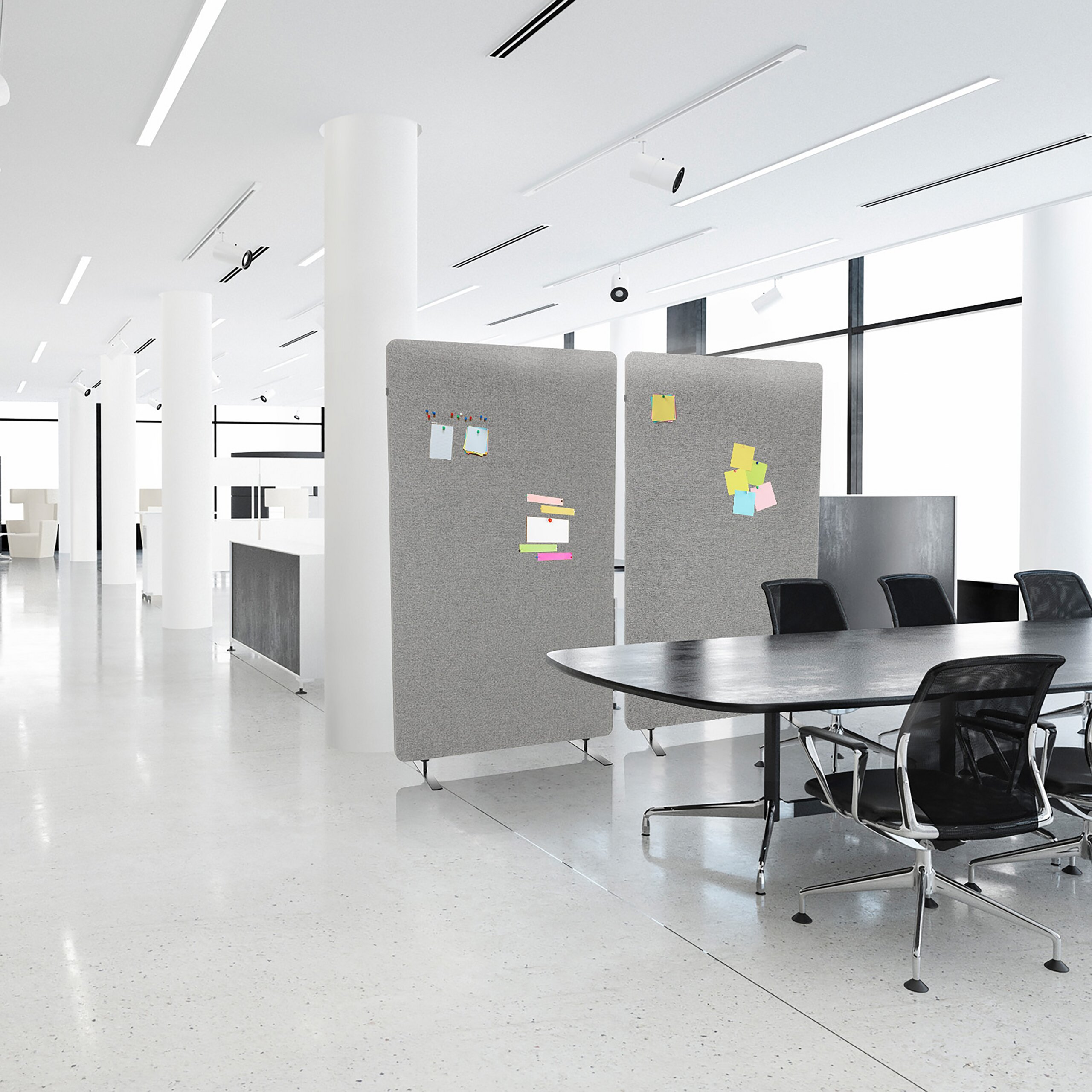 Ein modernes, helles Büro mit grossem Konferenztisch, grauen Akustikwänden und schwarzen Bürostühlen.