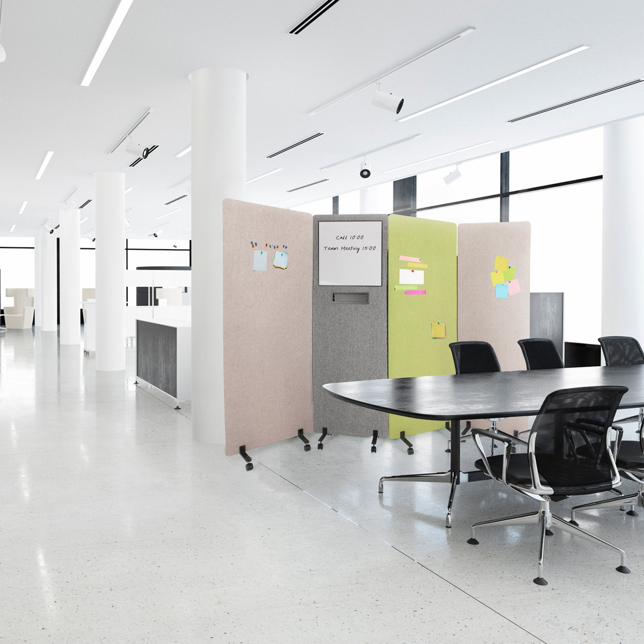 Moderne Bürofläche mit hellem Boden, großen Fenstern, Konferenztisch und bunten Trennwänden.