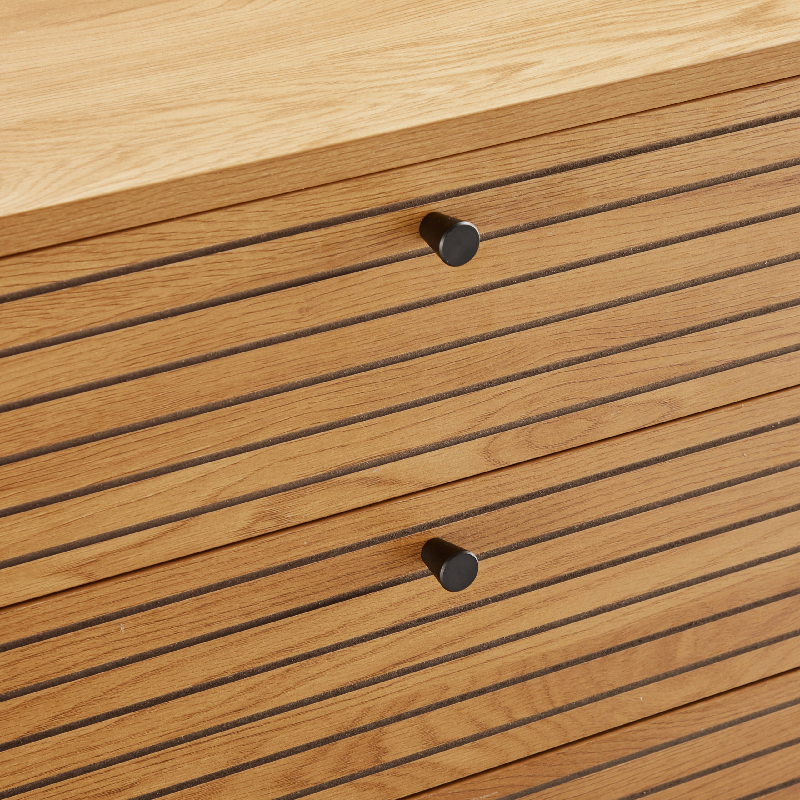 Holzkommode mit Lamellenfront und zwei schwarzen runden Knöpfen.