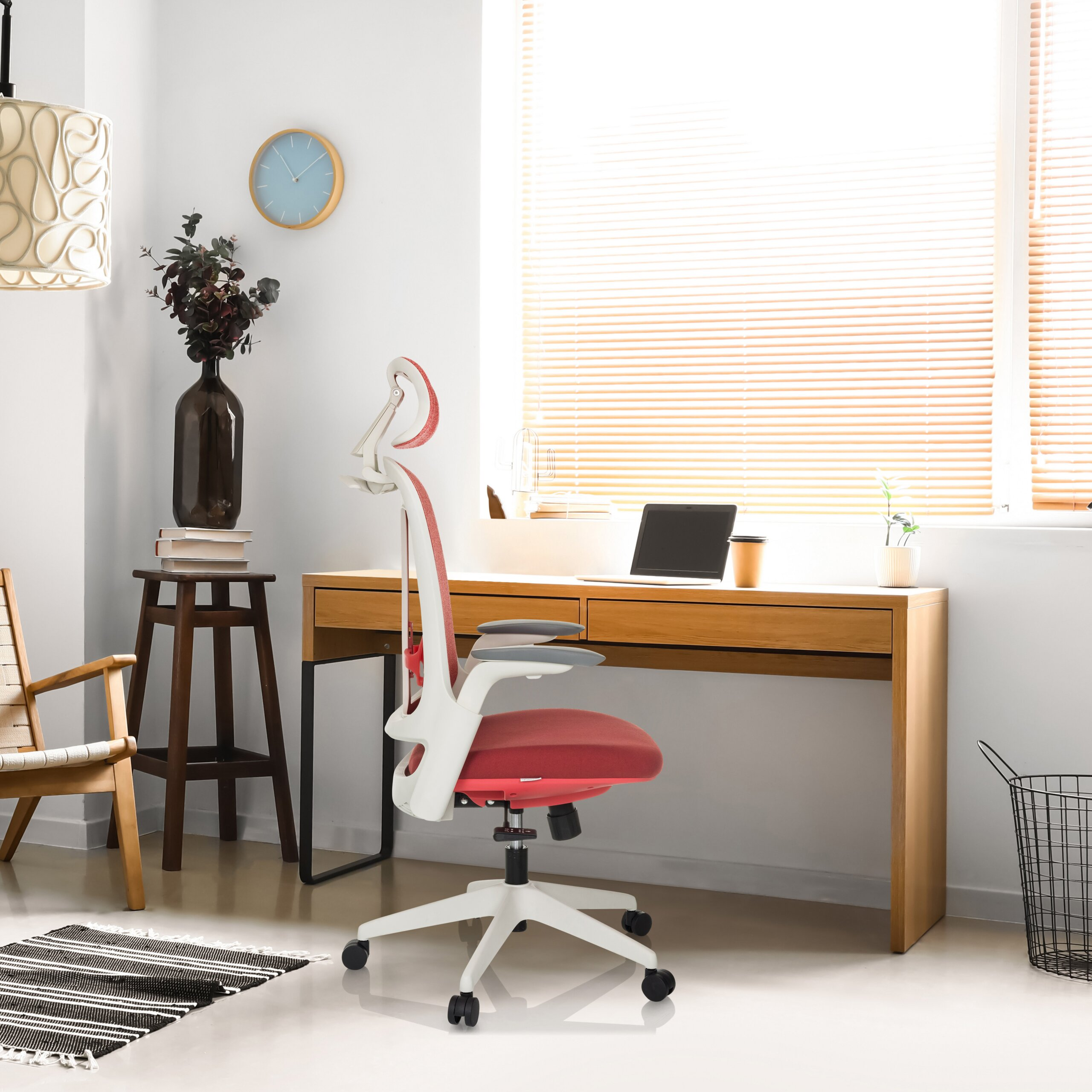 Moderne Arbeitsplatz mit einem rot-weißen Schreibtischstuhl, Holztisch, Laptop und großen Fenster mit Jalousien.