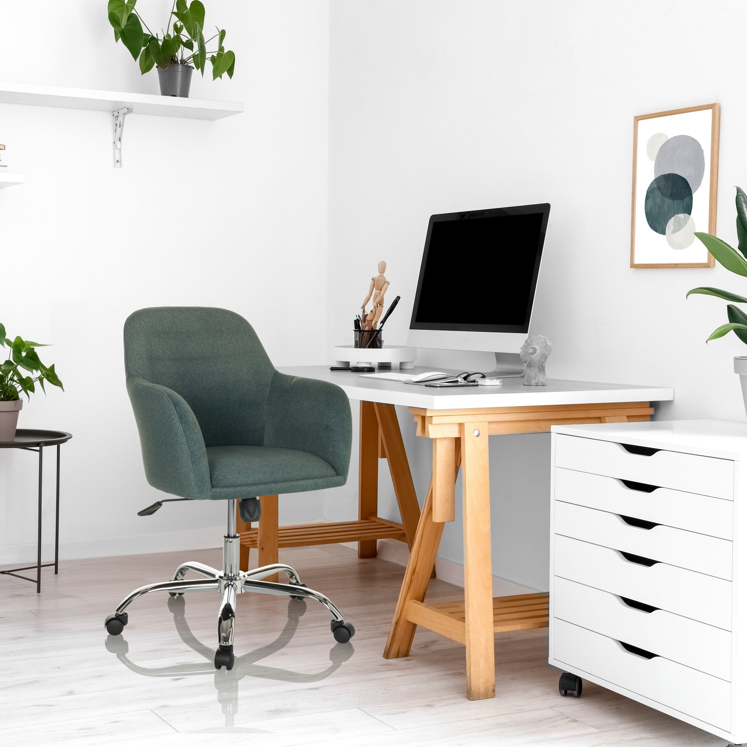 Ein moderner Arbeitsplatz mit grünem Bürostuhl, Holztisch, Computer, Pflanzen und abstrakter Kunst.