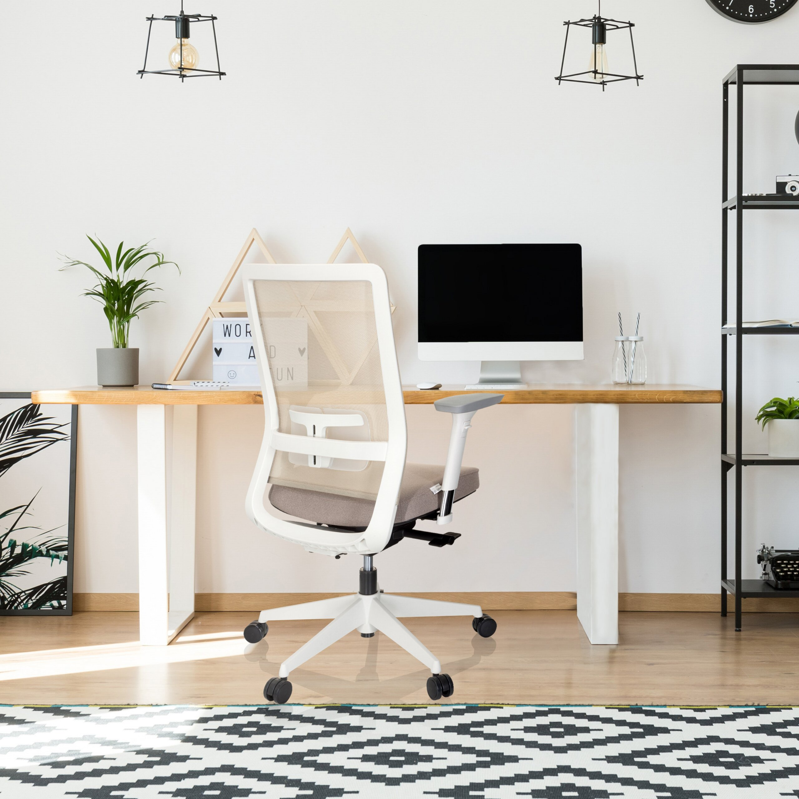 Ein weißer Bürostuhl steht vor einem Holztisch mit einem Computer in einem modernen Arbeitszimmer.