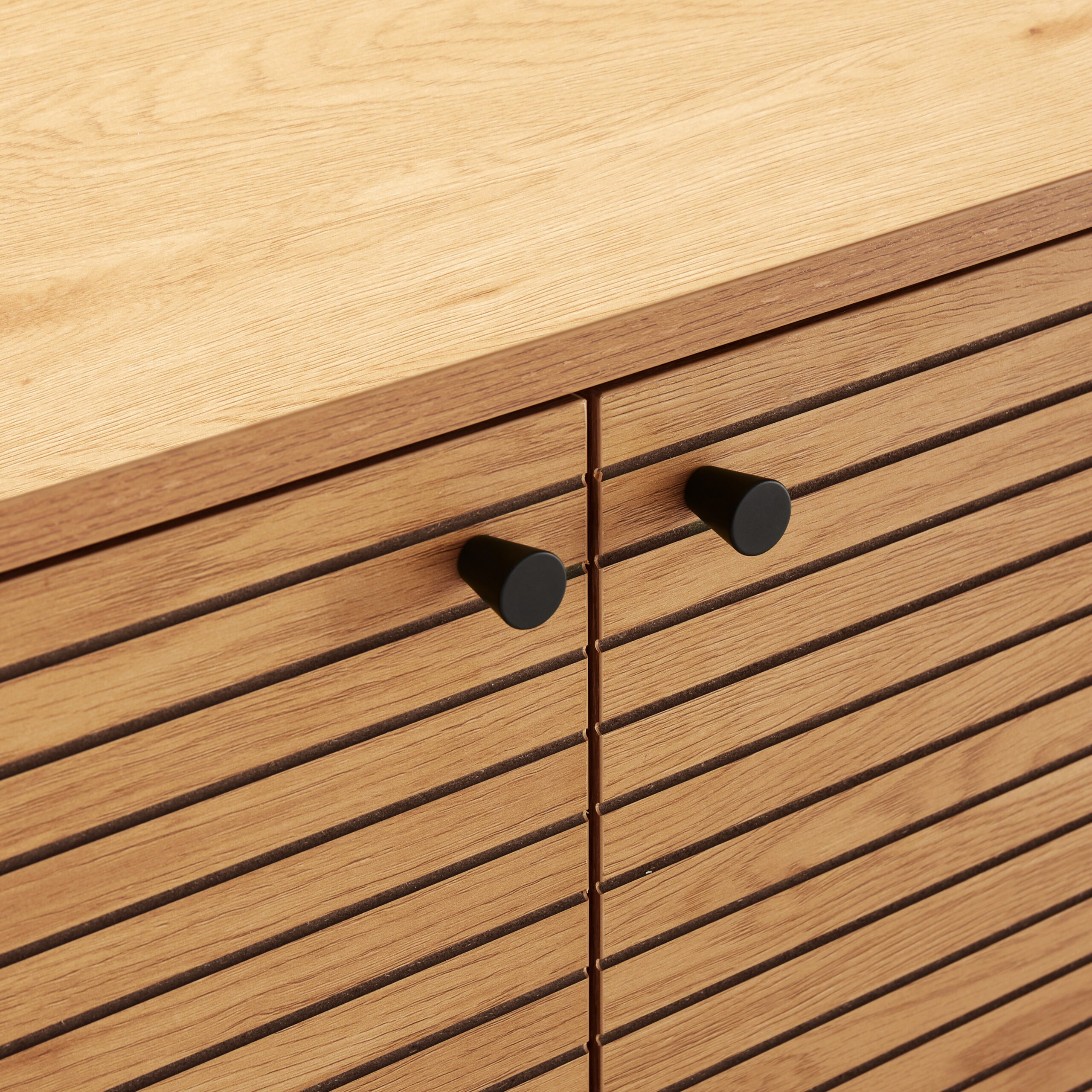 Holzschrank mit Lamellentüren und zwei runden schwarzen Knöpfen.