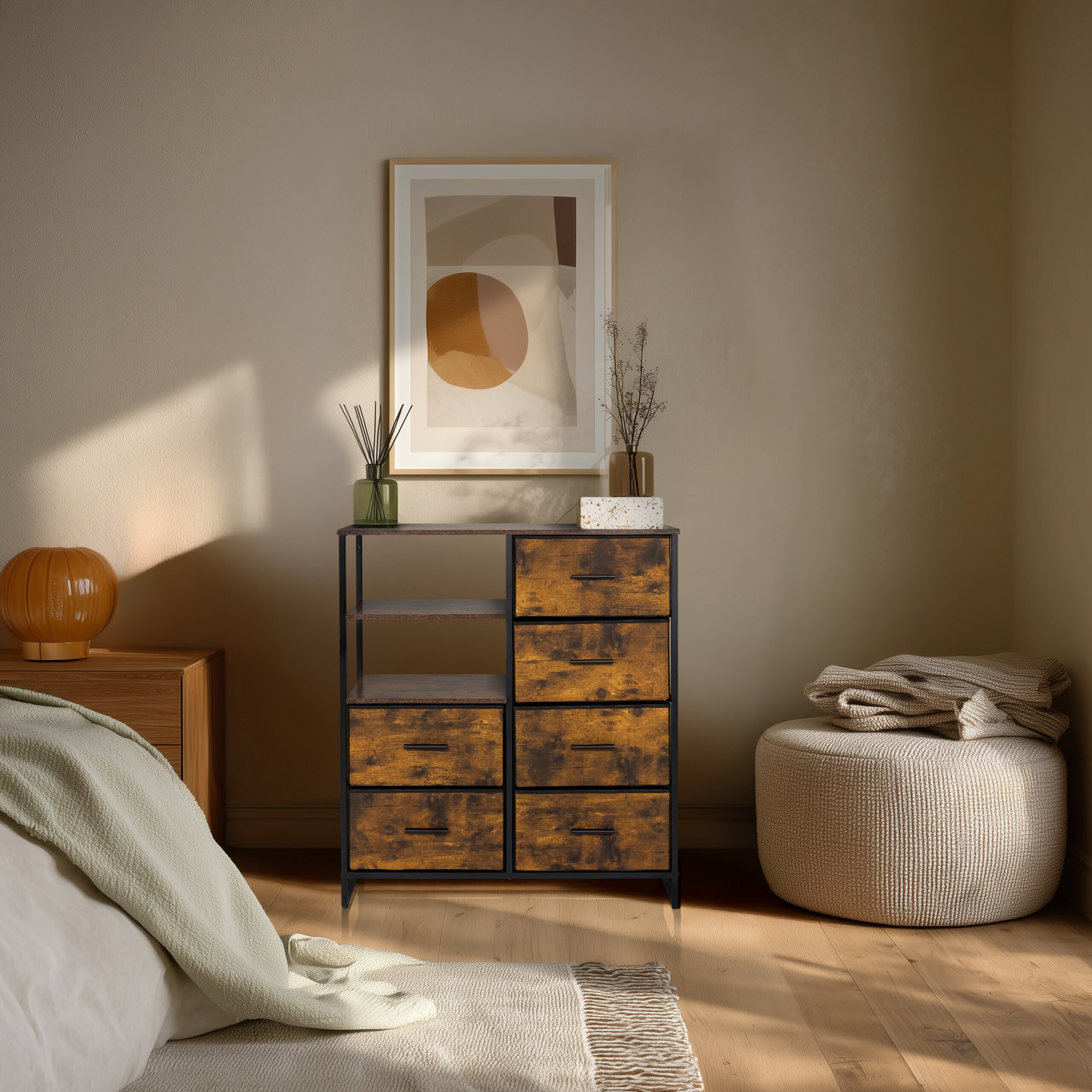 Gemütliches Schlafzimmer mit Holzkommode, gerahmtem Bild, Nachttisch und beigem Pouf mit Decke.