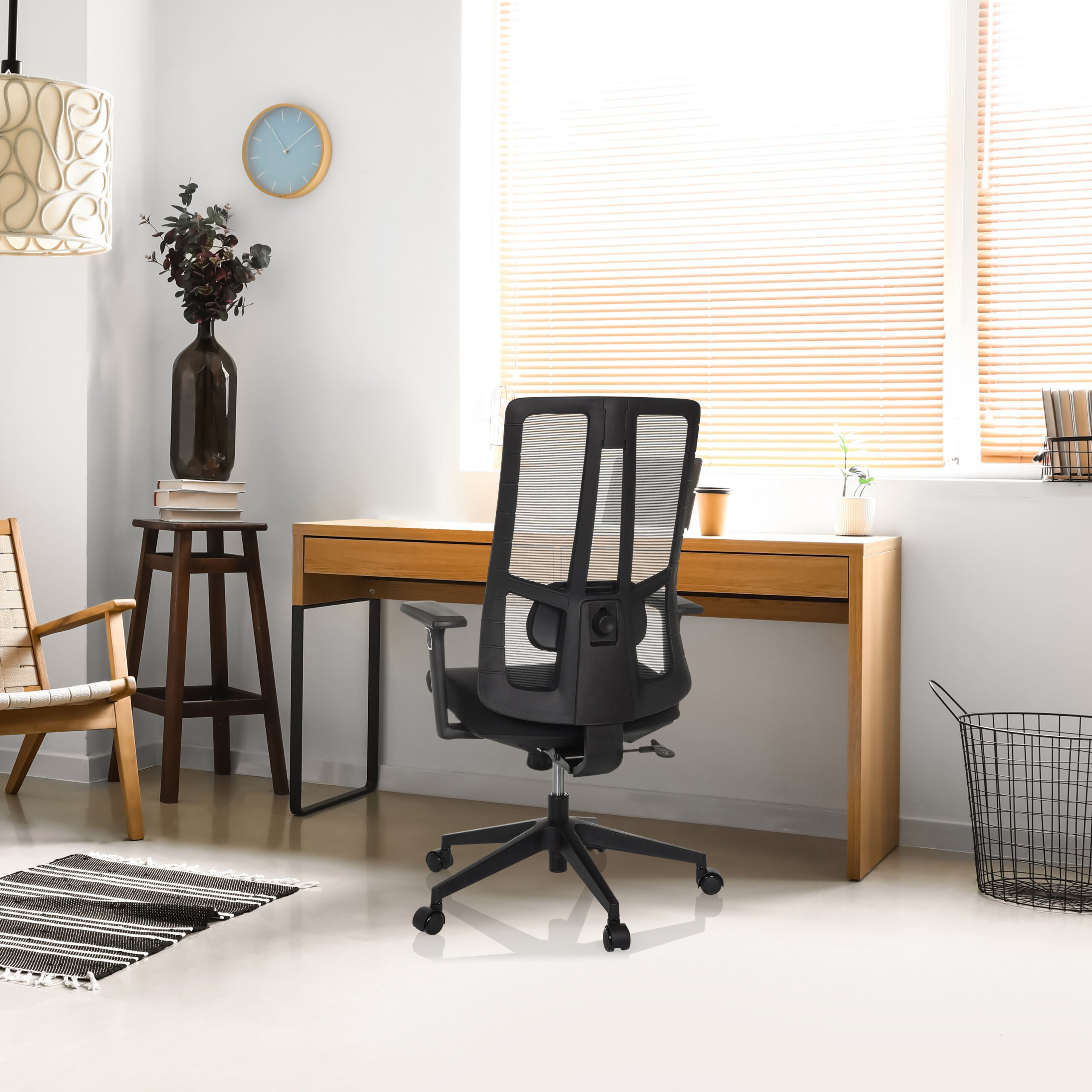 Ein modernes Homeoffice mit Holztisch, schwarzem Bürostuhl, Lampe und grossem Fenster mit Jalousien.