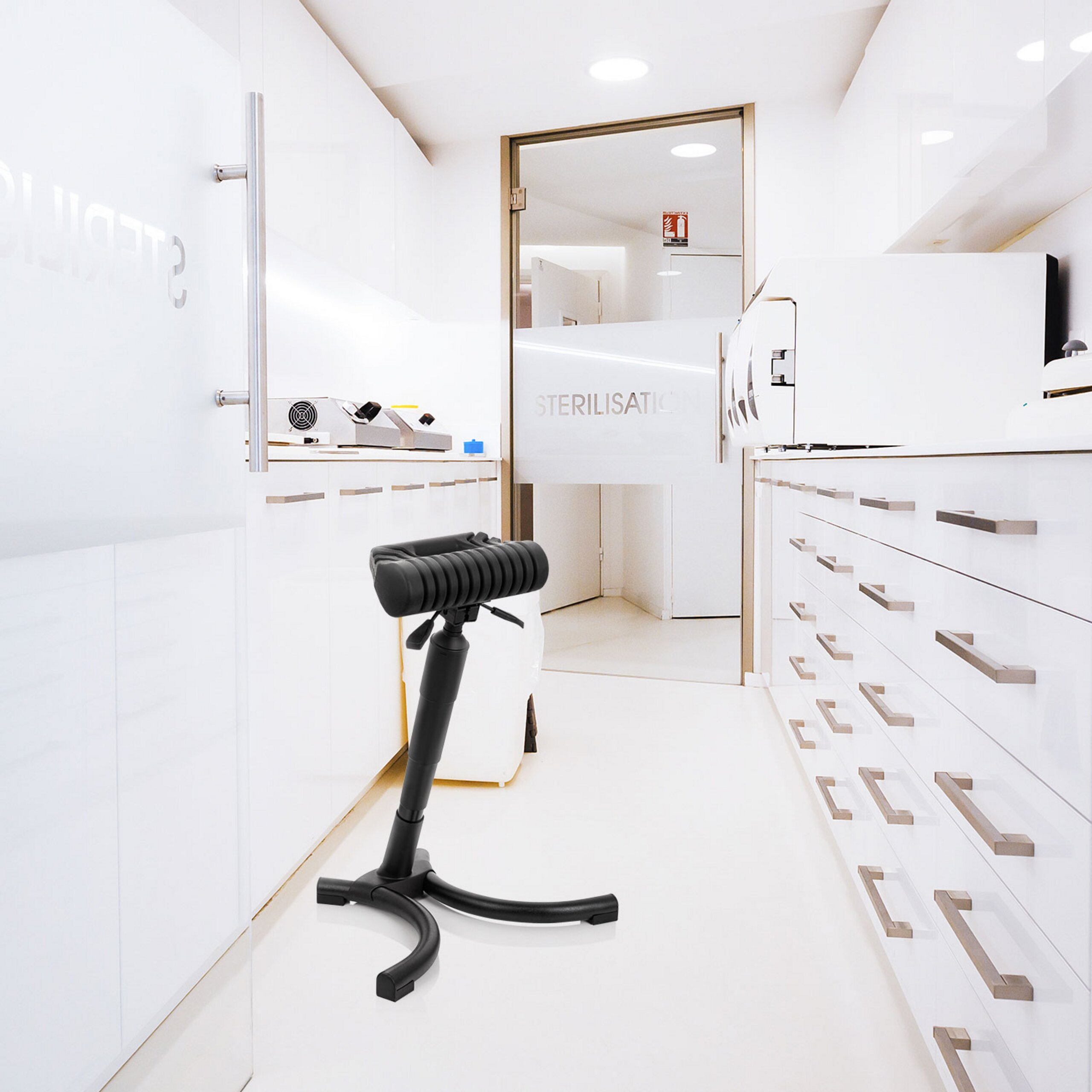 Ein schwarzer ergonomischer Hocker in einem modernen, weißen Sterilisationsraum mit Schränken.