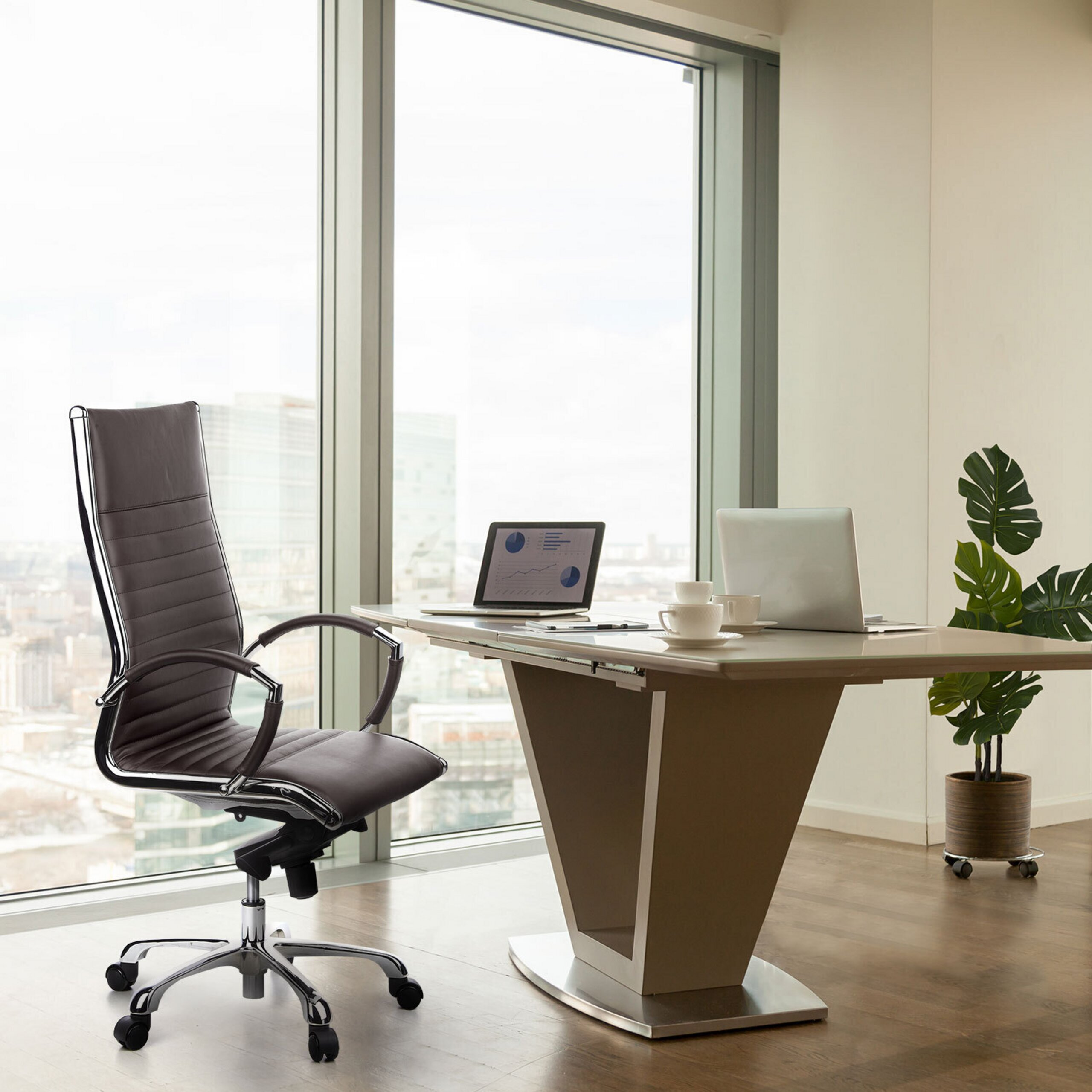 Ein modernes Büro mit einem braunen Ledersessel, Schreibtisch mit zwei Laptops, Kaffeetassen und einer Topfpflanze.