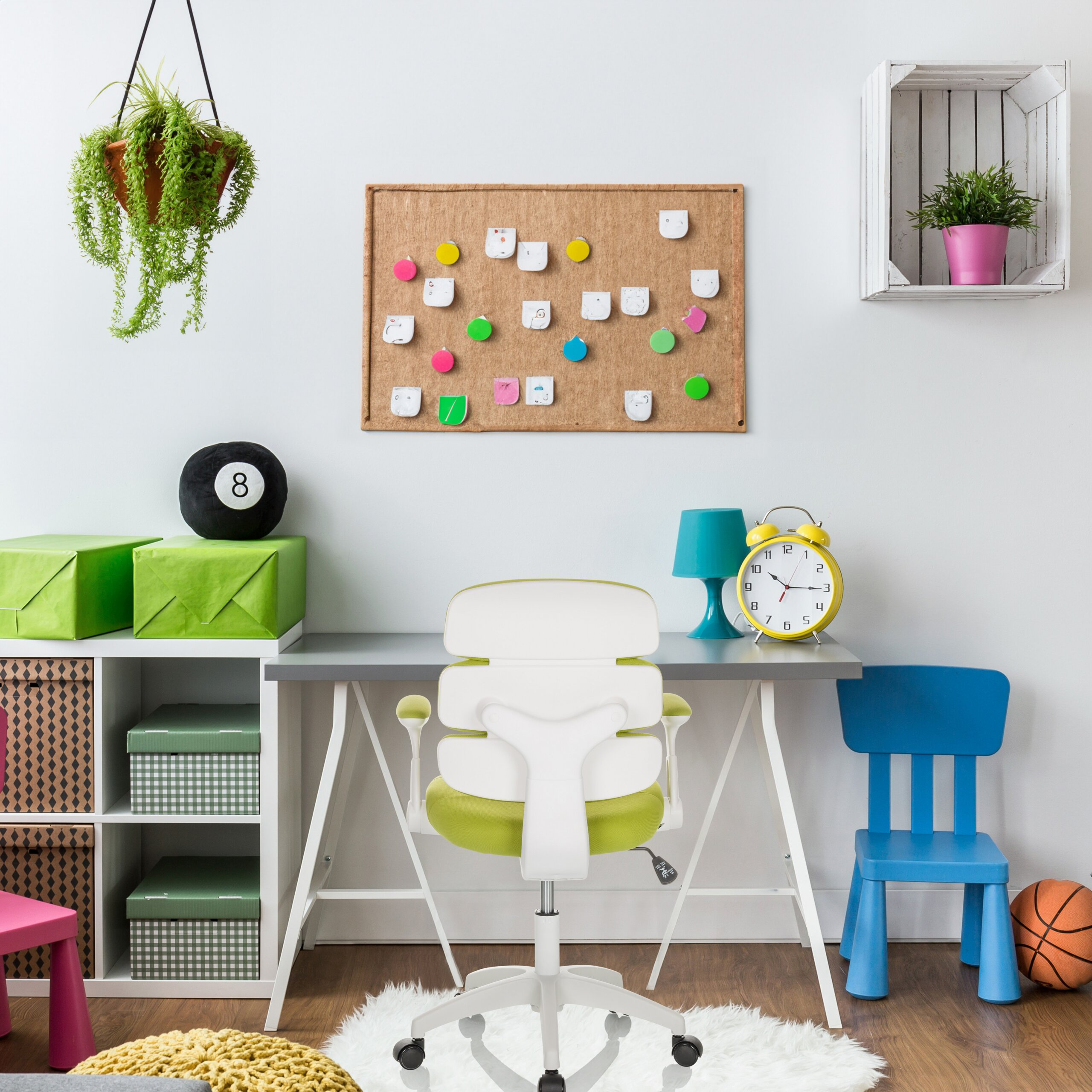 Buntes Arbeitszimmer mit Schreibtisch, weißem Stuhl, blauem Stuhl, Pinnwand, Regal und Pflanzen.