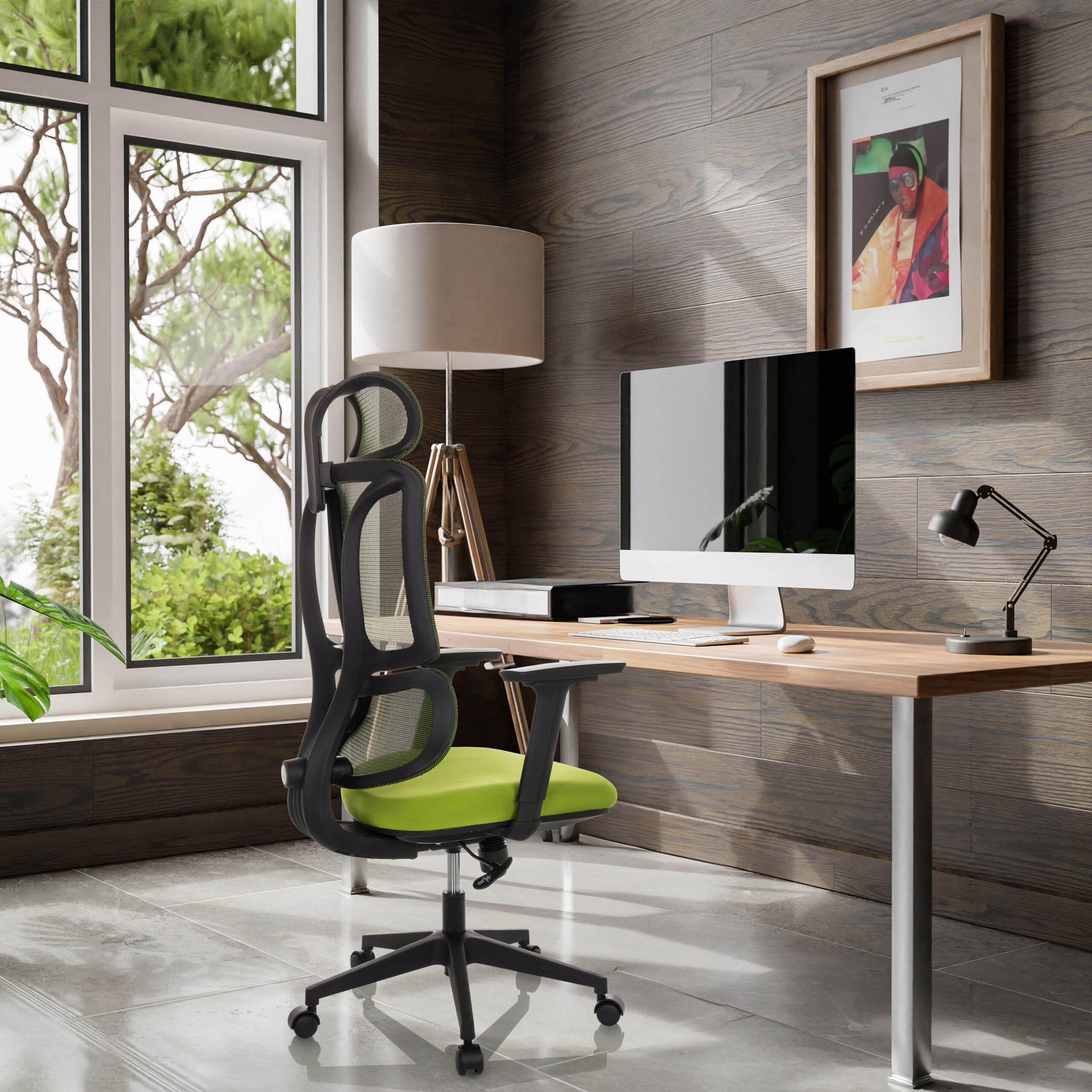 Büro mit grün-schwarzem Stuhl, Holztisch, Computer, Lampe und gerahmtem Bild vor Holzverkleidung.