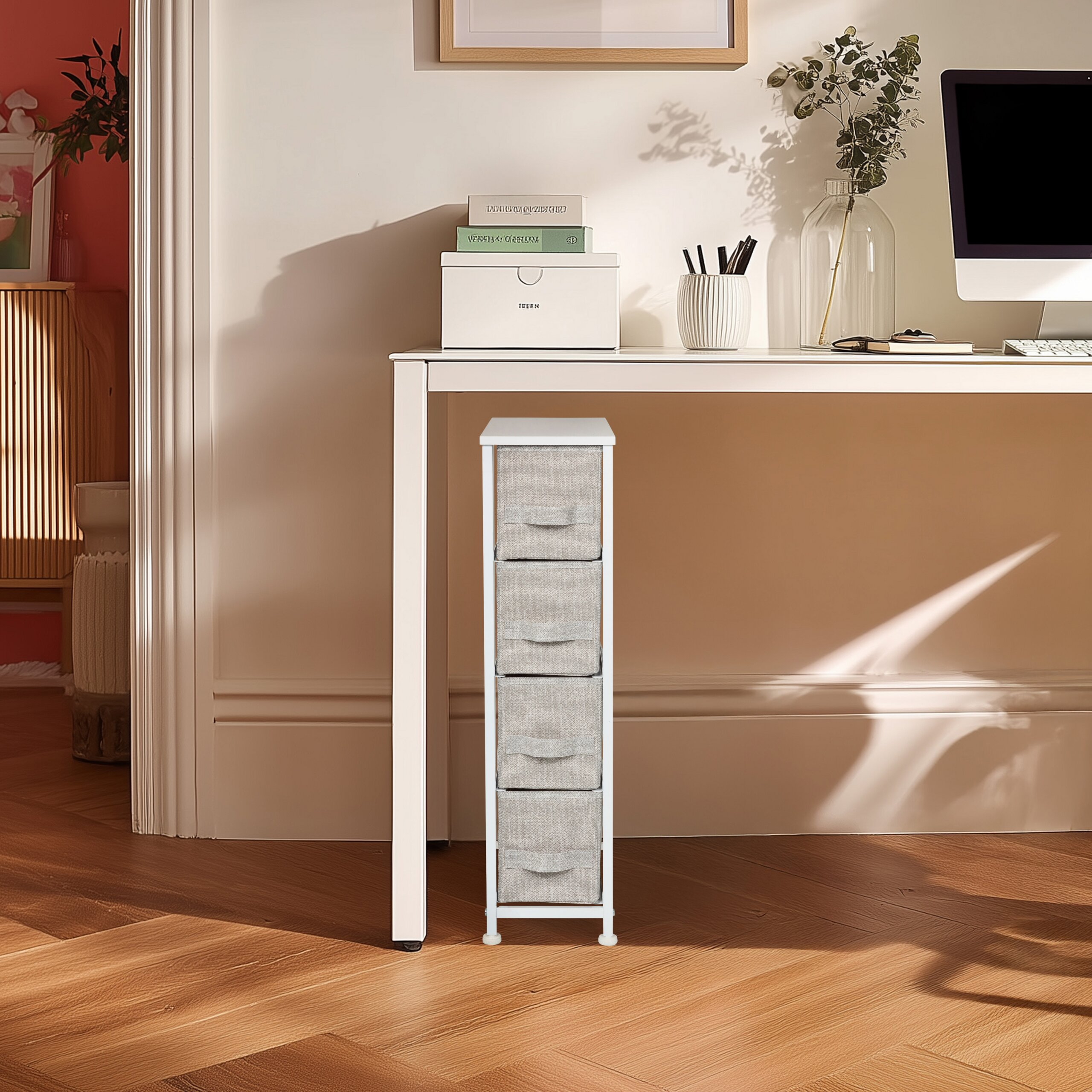 Ein schlanker Schrank mit vier grauen Stoffschubladen steht unter einem weißen Schreibtisch.