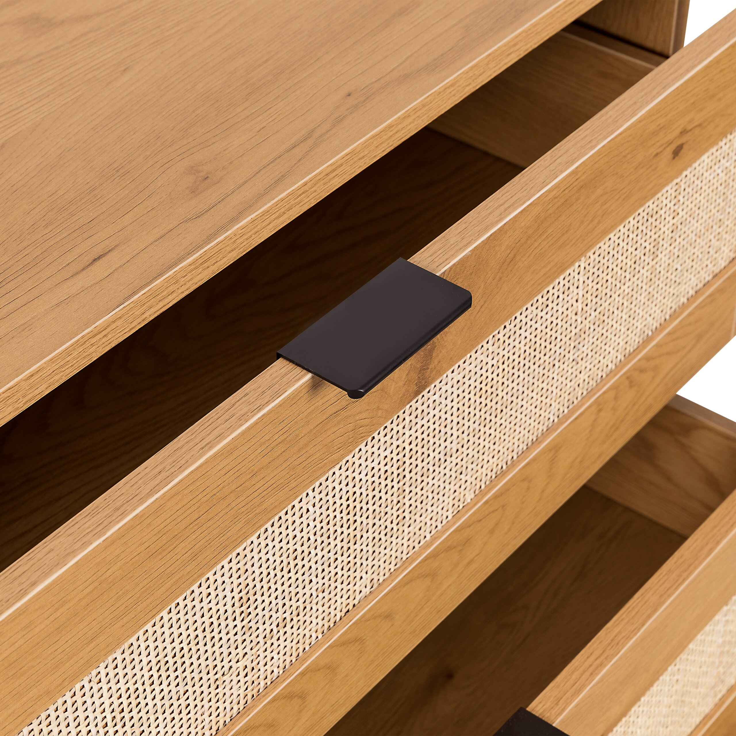 Holzkommode mit offenen Schubladen, schwarzem Griff und Rattandetail auf der Vorderseite.