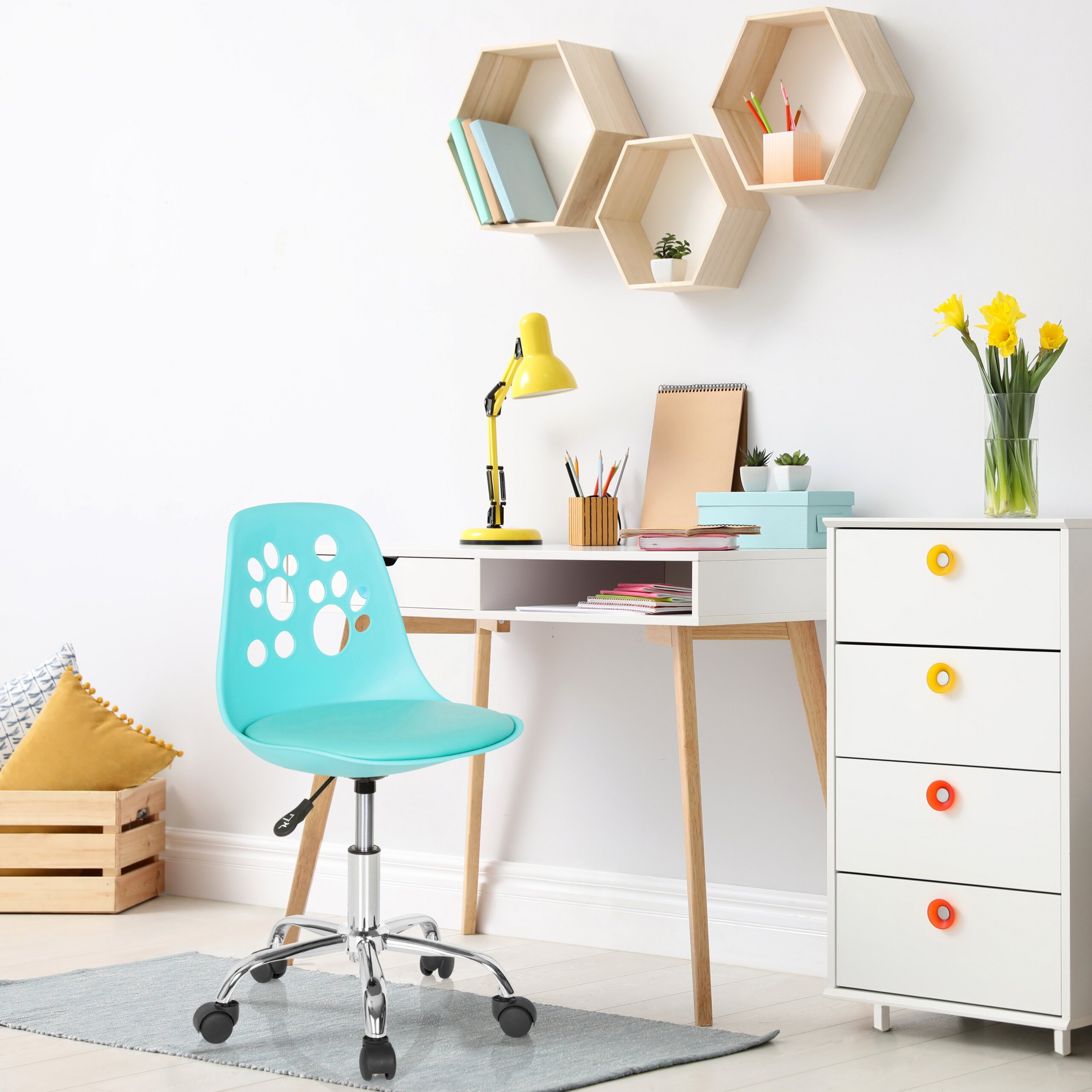 Ein weißer Schreibtisch mit blauem Stuhl, gelber Lampe und Hexagon-Regalen an der Wand.