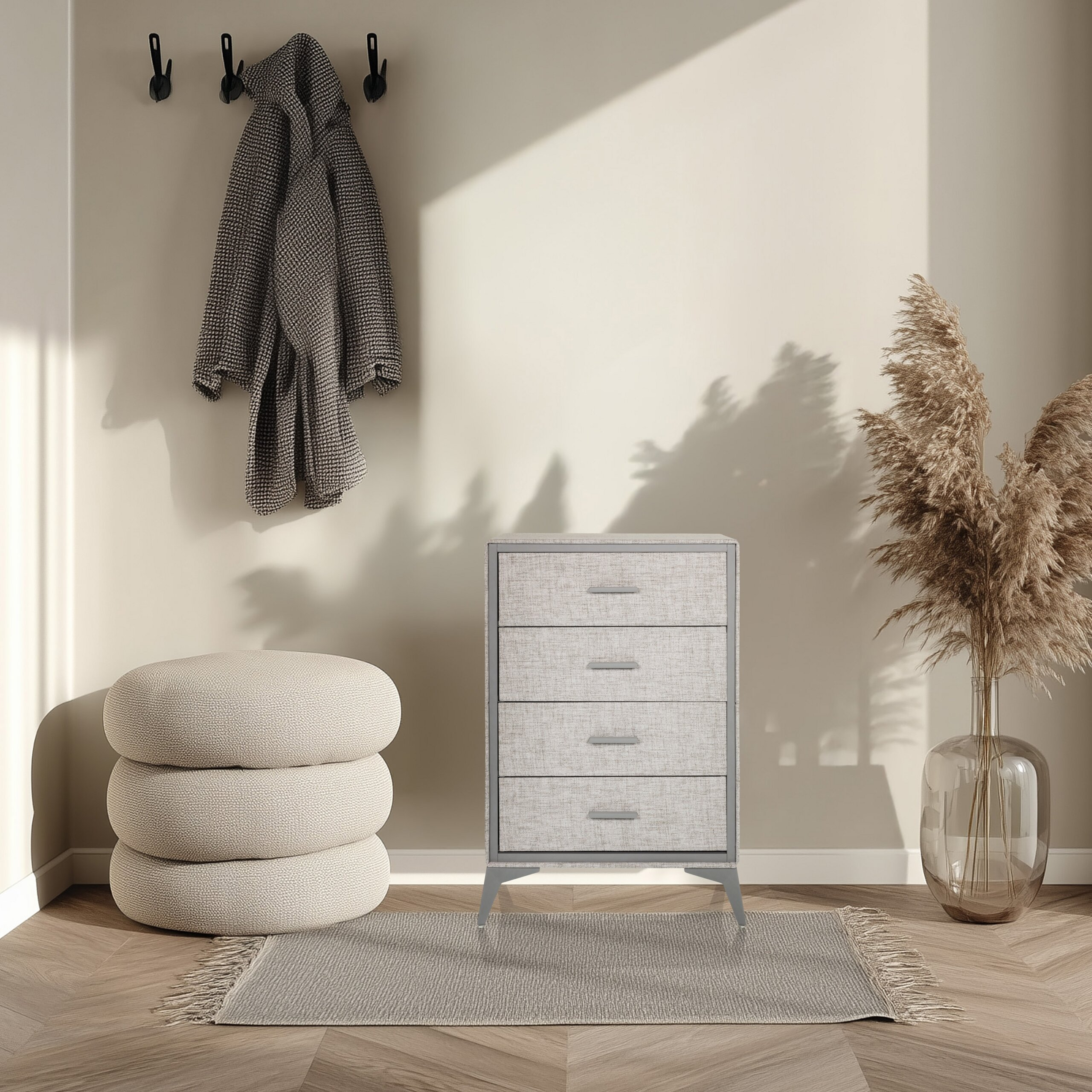 Ein beiges Zimmer mit grauer Kommode, runden Kissen, einem grauen Bademantel und Pampasgras in einer Glasvase.