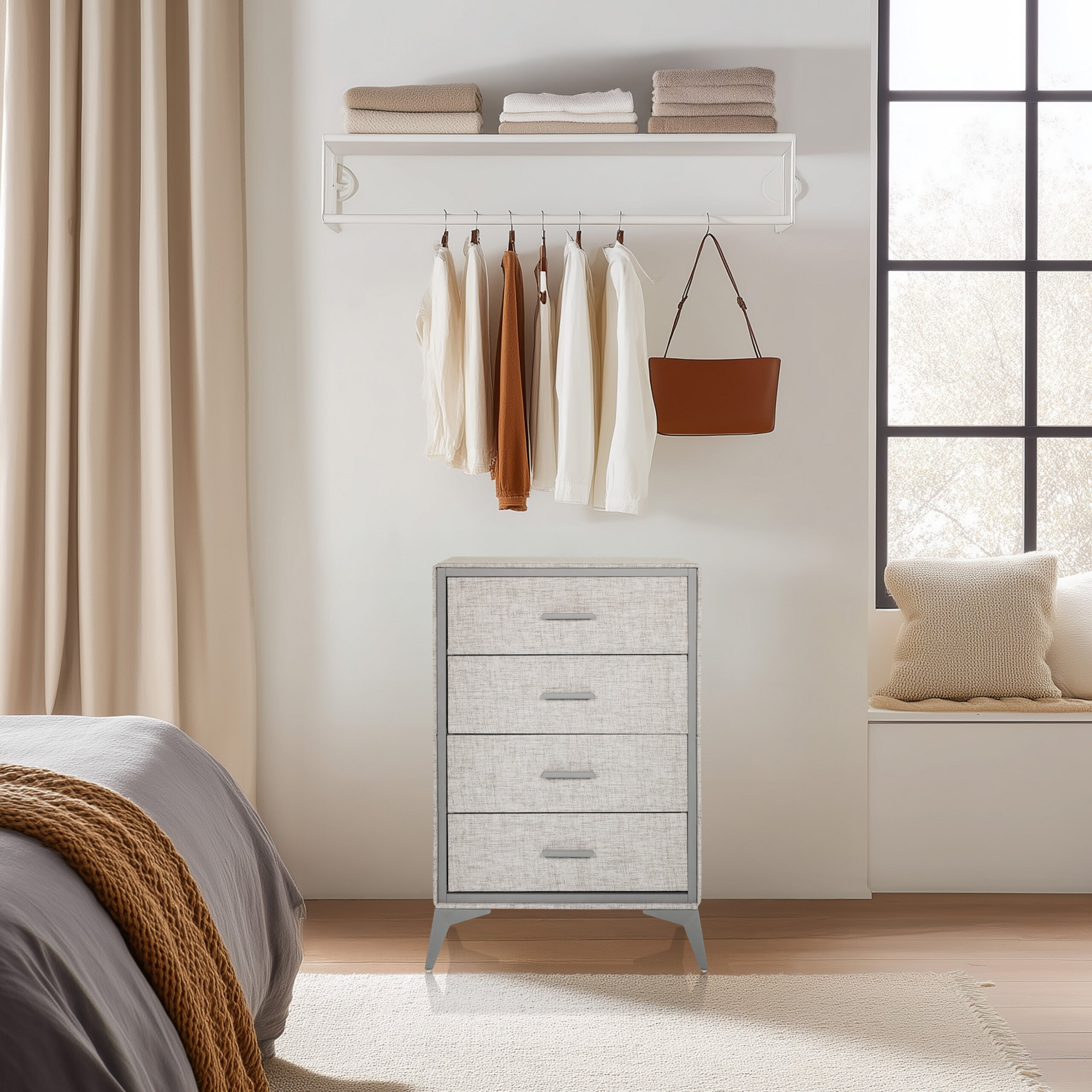 Eine weiße Kommode mit vier Schubladen, darüber hängende Kleidung und Handtücher in einem Schlafzimmer.