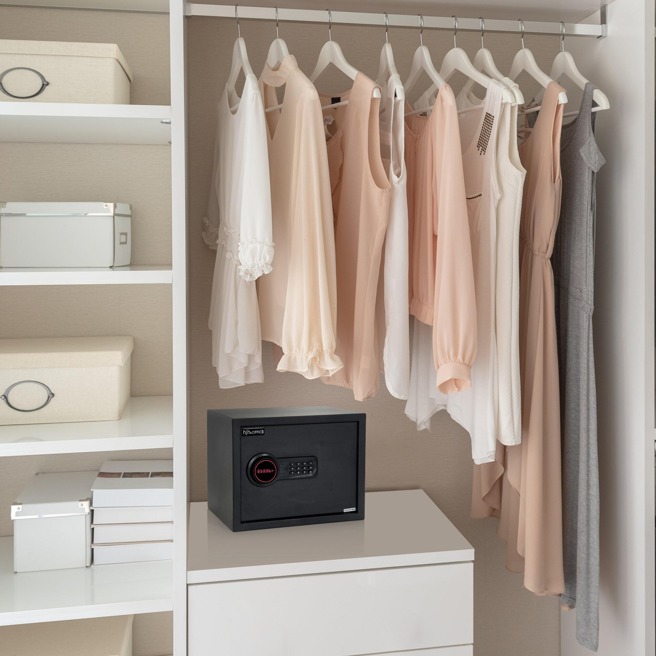 Kleiderschrank mit hellen Kleidungsstücken, geordneten Regalen und einem elektronischen Tresor auf der Kommode.