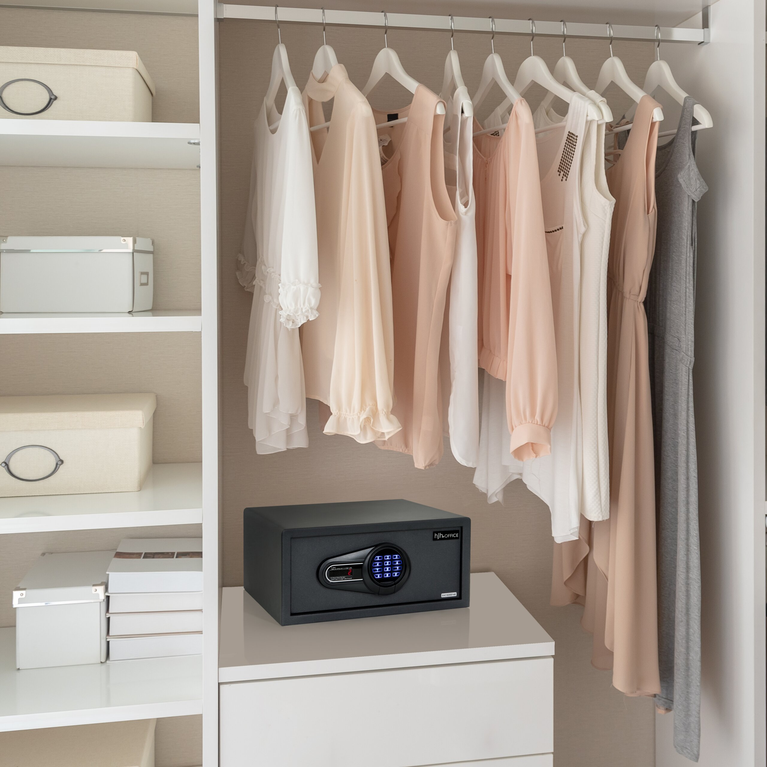 Kleiderschrank mit hellen Kleidern auf Bügeln und einem digitalen Safe unten.